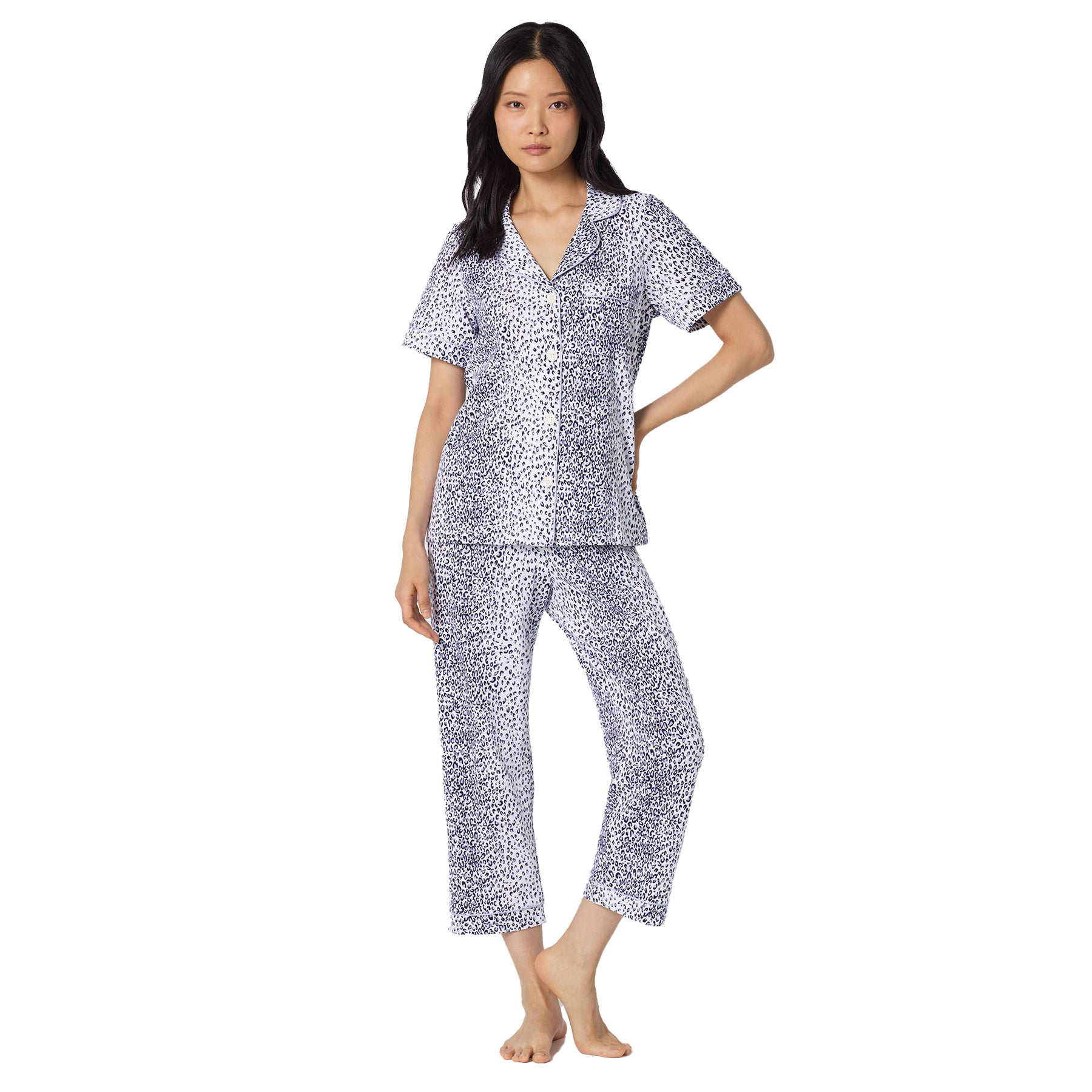 Woman wearing a white and navy leopard print pyjama set with short sleeve button-front top and relaxed cropped pants.