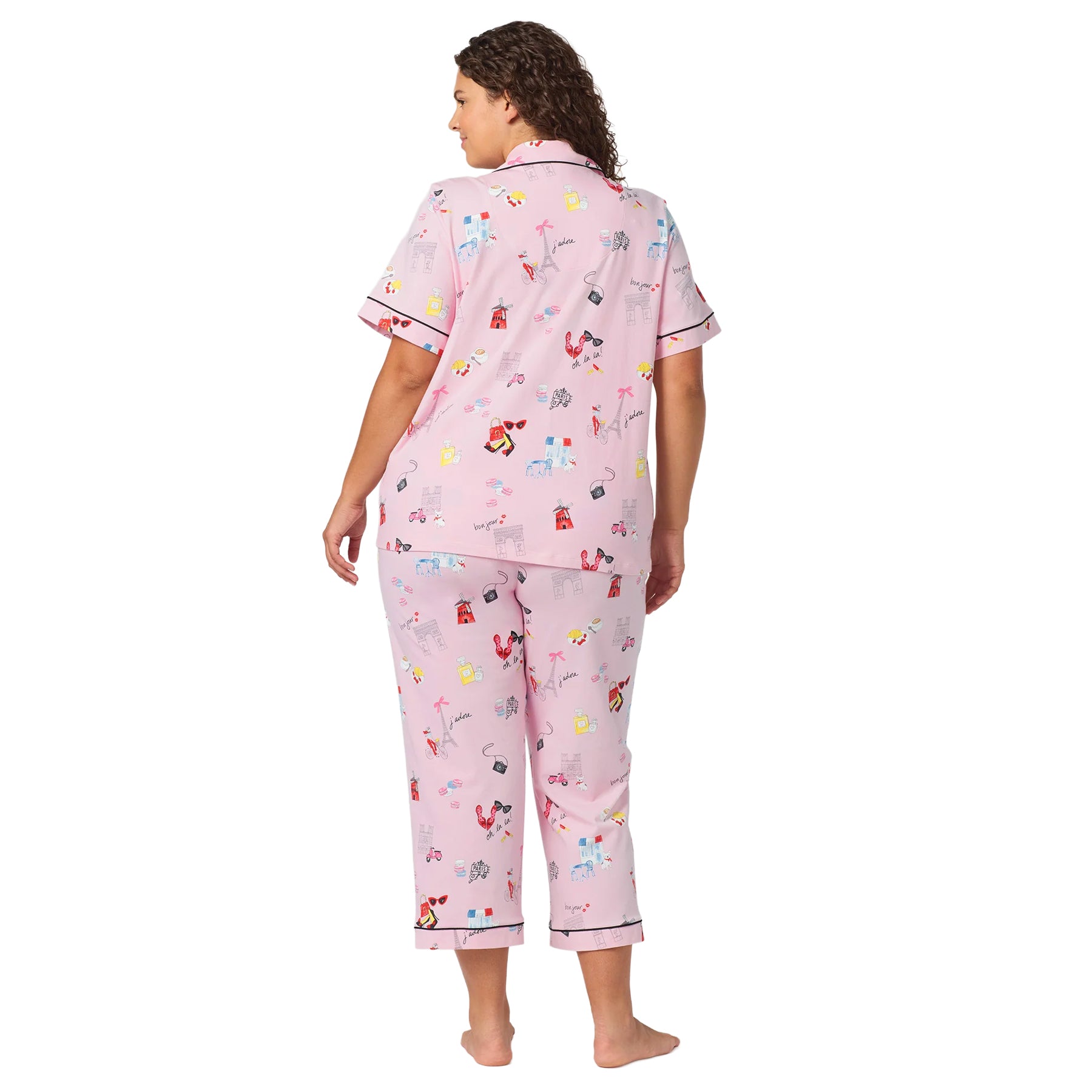 Back view of a plus-size woman wearing a pink Paris print pajama set with short sleeves, cropped pants and black piping.