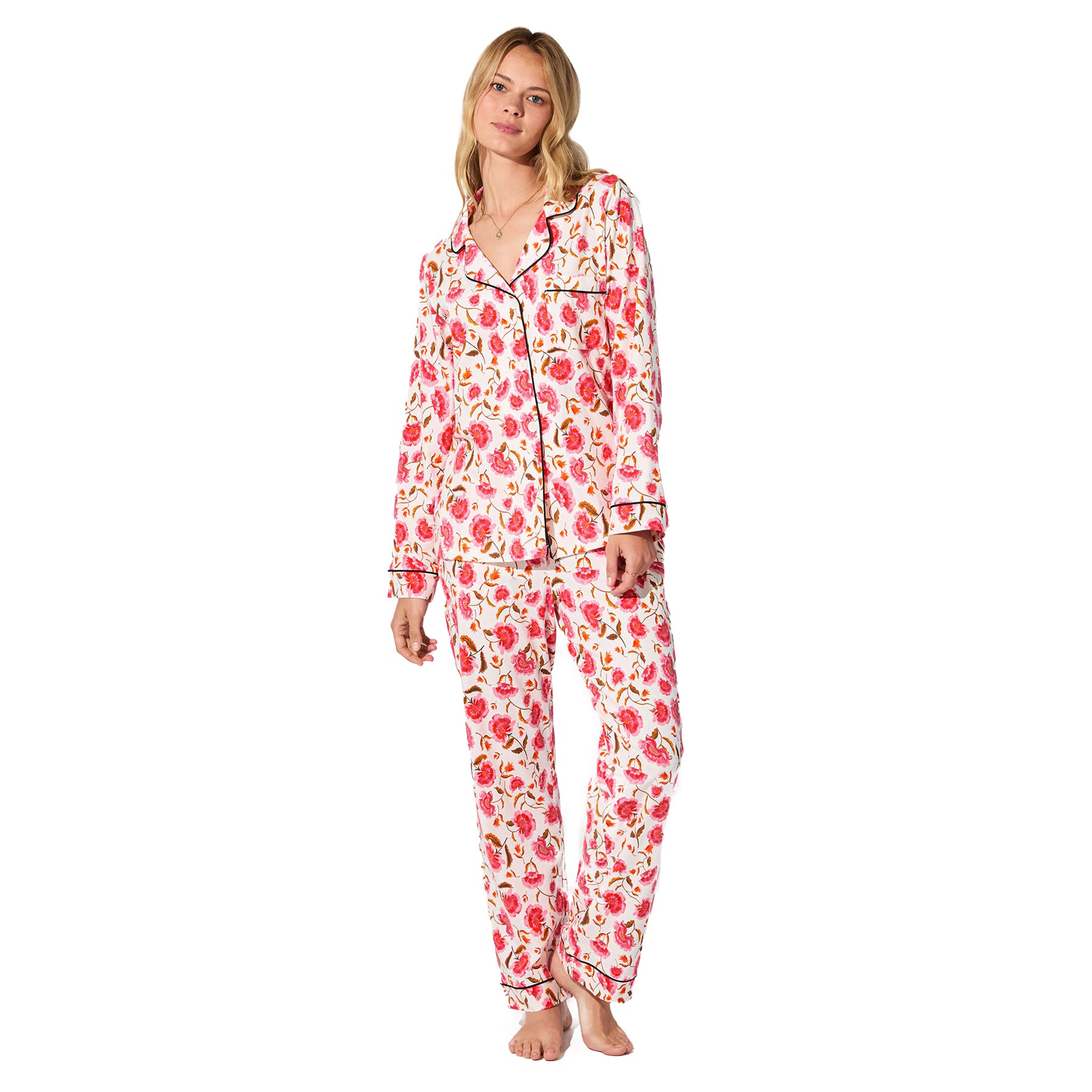 Full view of woman wearing white floral pyjama set with long sleeves and pants.