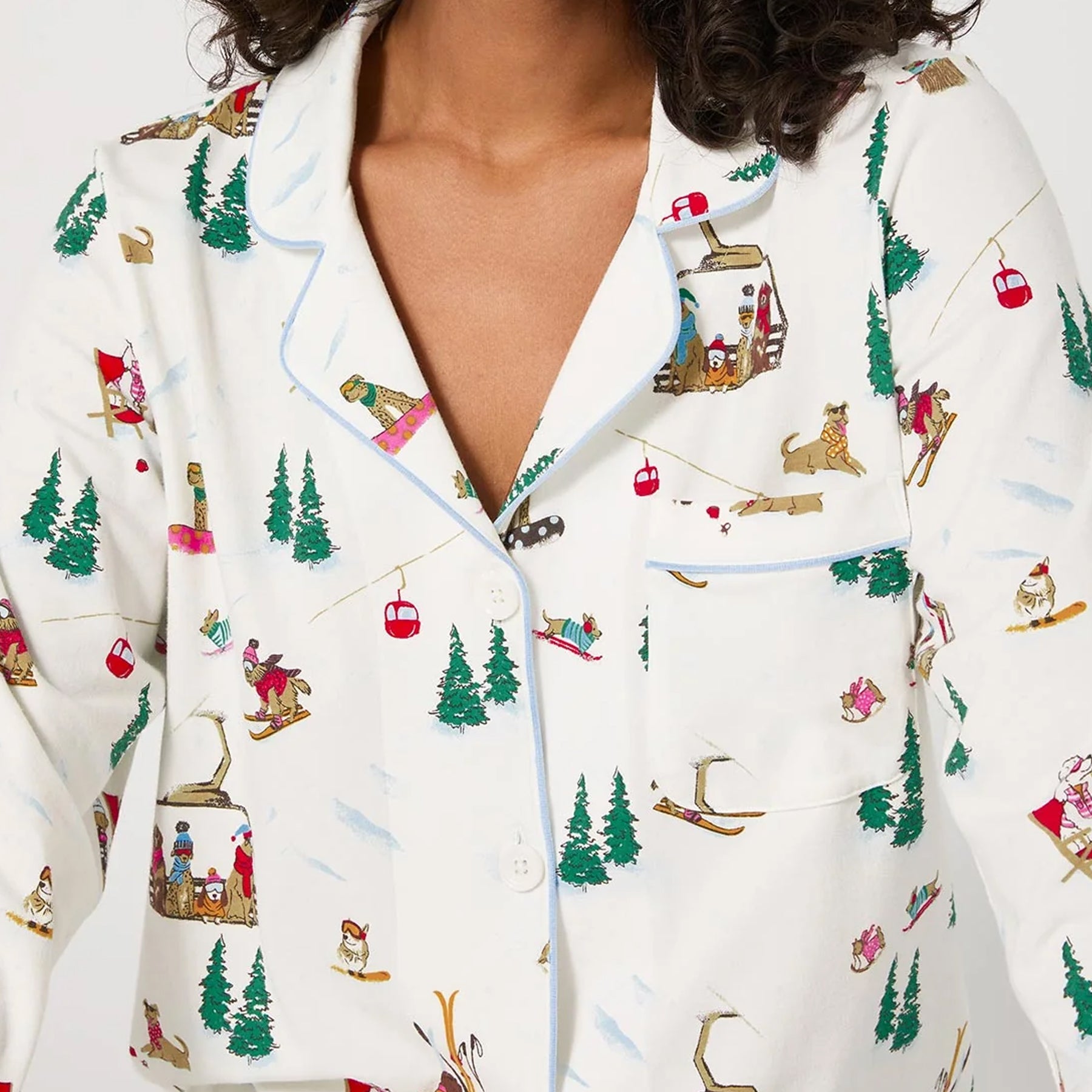 Close-up of ski-themed cotton pyjama top showing colourful winter print with dogs, trees, and gondolas.