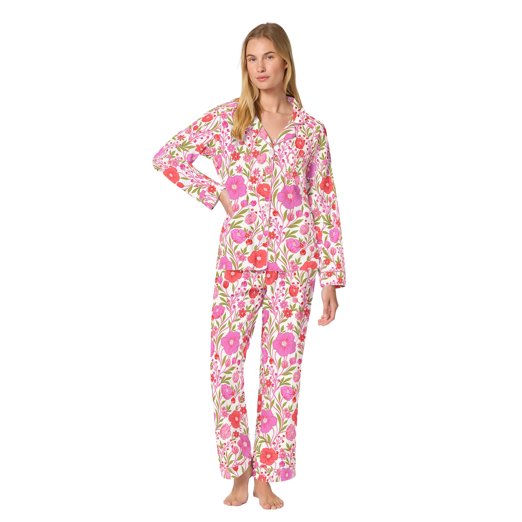 Woman wearing a white button-front pajama set with pink and coral floral print, long sleeves and full-length pants.
