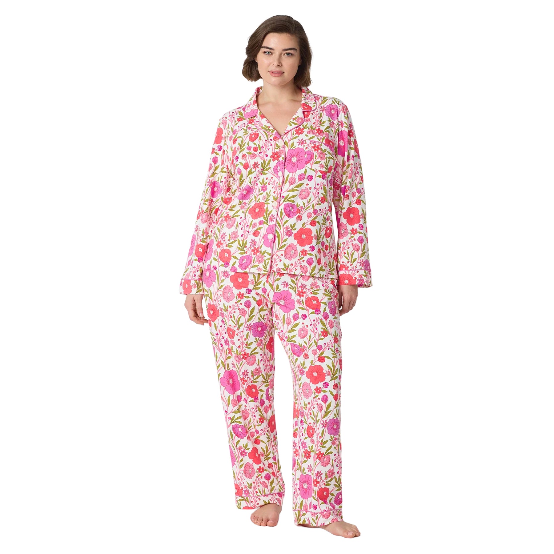 Plus-size woman wearing a white long-sleeve pajama set with pink floral print, button-front top and full-length pants.