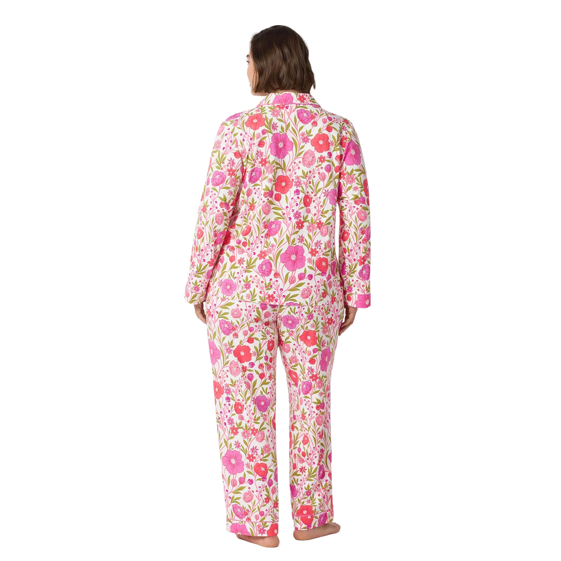 Back view of a plus-size woman wearing a white pajama set with vibrant pink floral print, long sleeves and full-length pants.