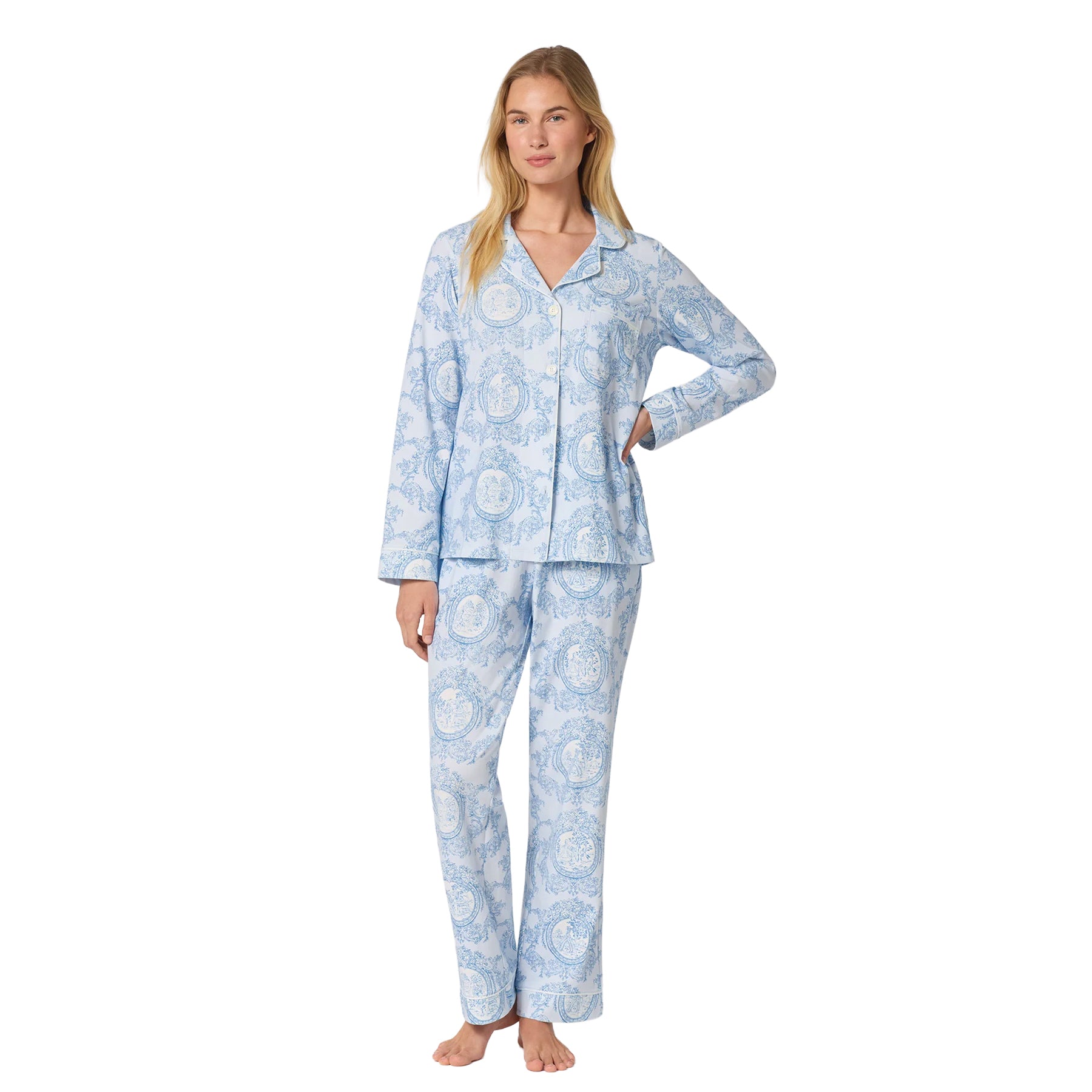 Woman wearing a light blue long-sleeve pajama set with an elegant blue toile print, button-front top and full-length pants.