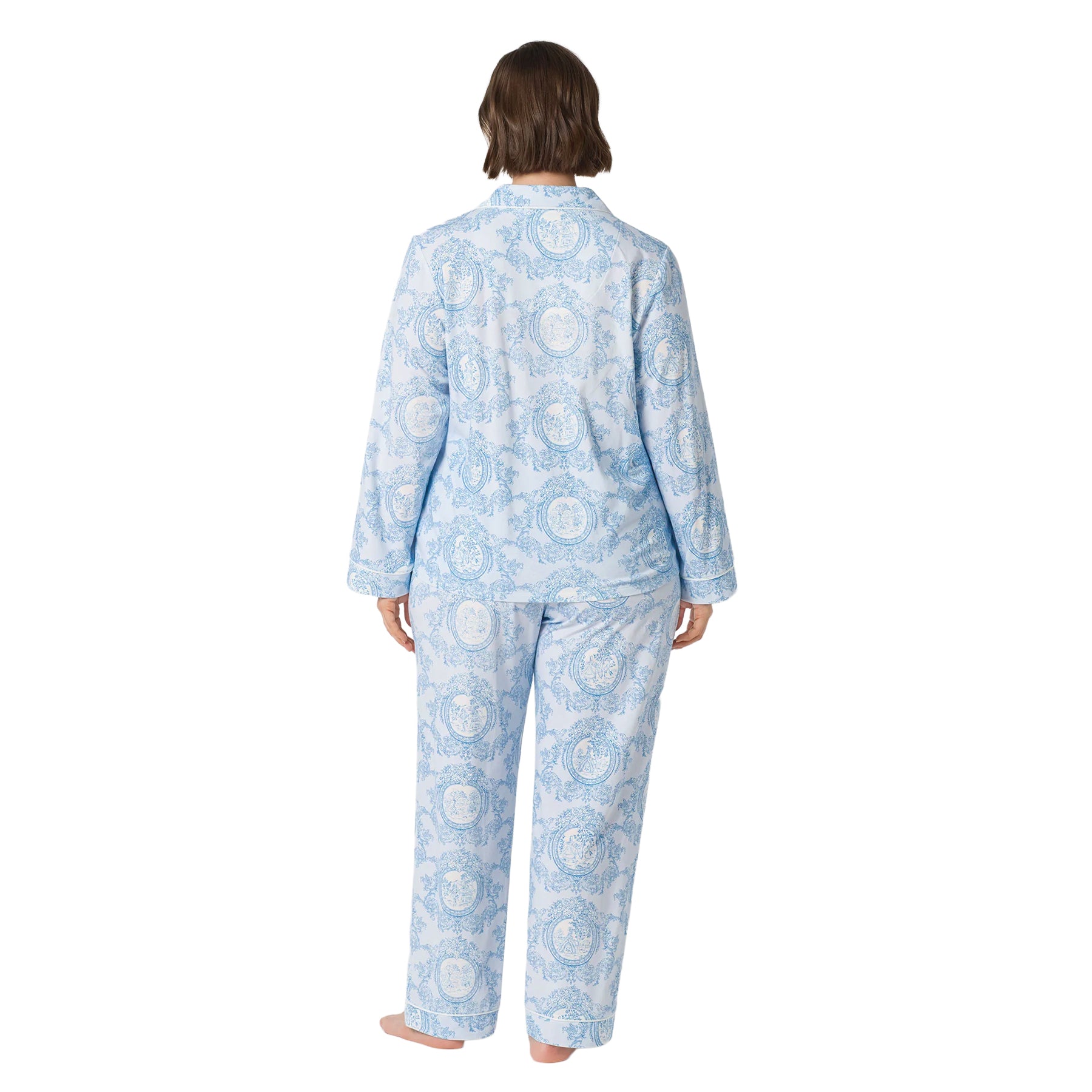 Back view of a plus-size woman wearing a light blue pajama set with an intricate blue toile print and full-length pants.