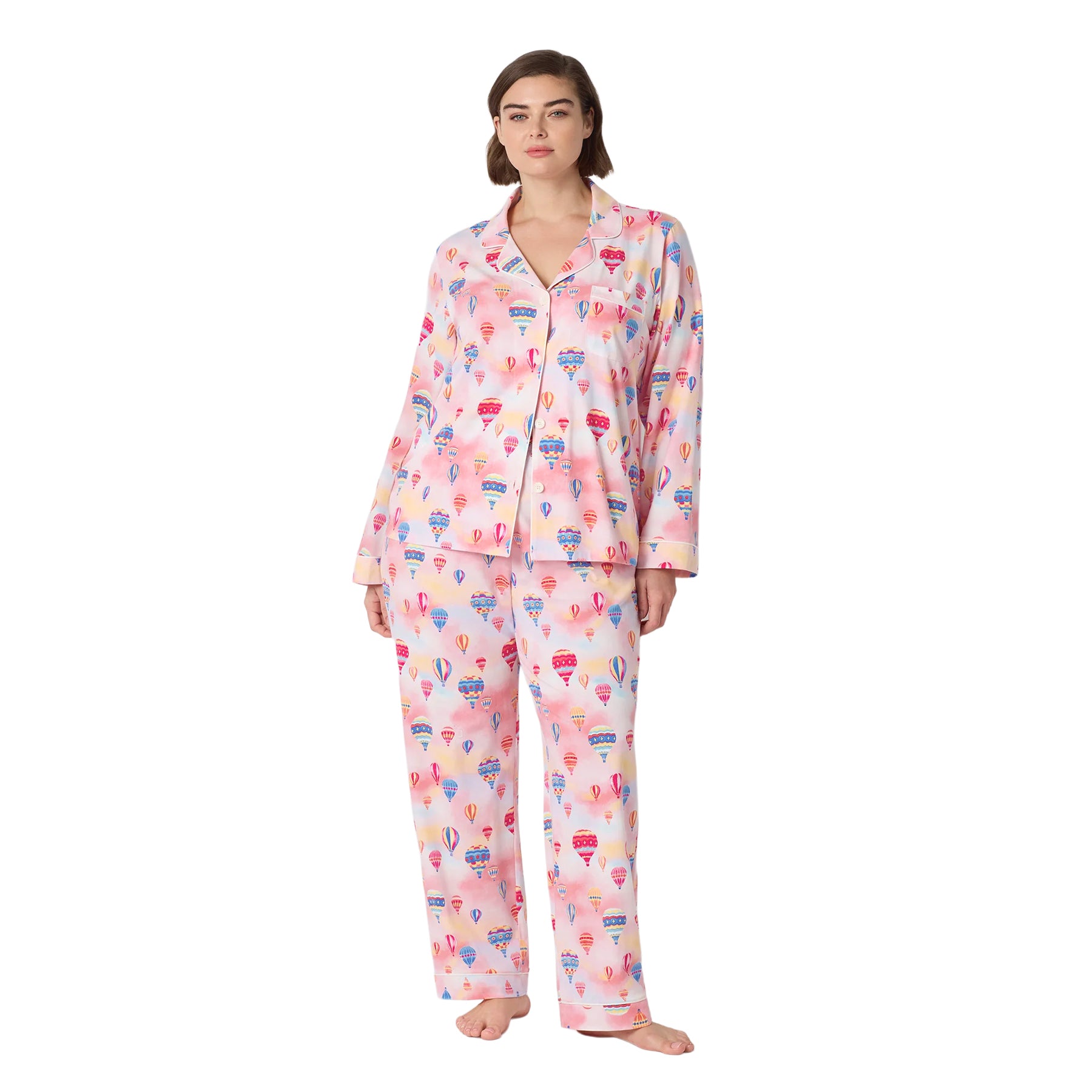 Plus-size woman wearing a pink long-sleeve pajama set with colourful hot air balloon print and full-length pants.