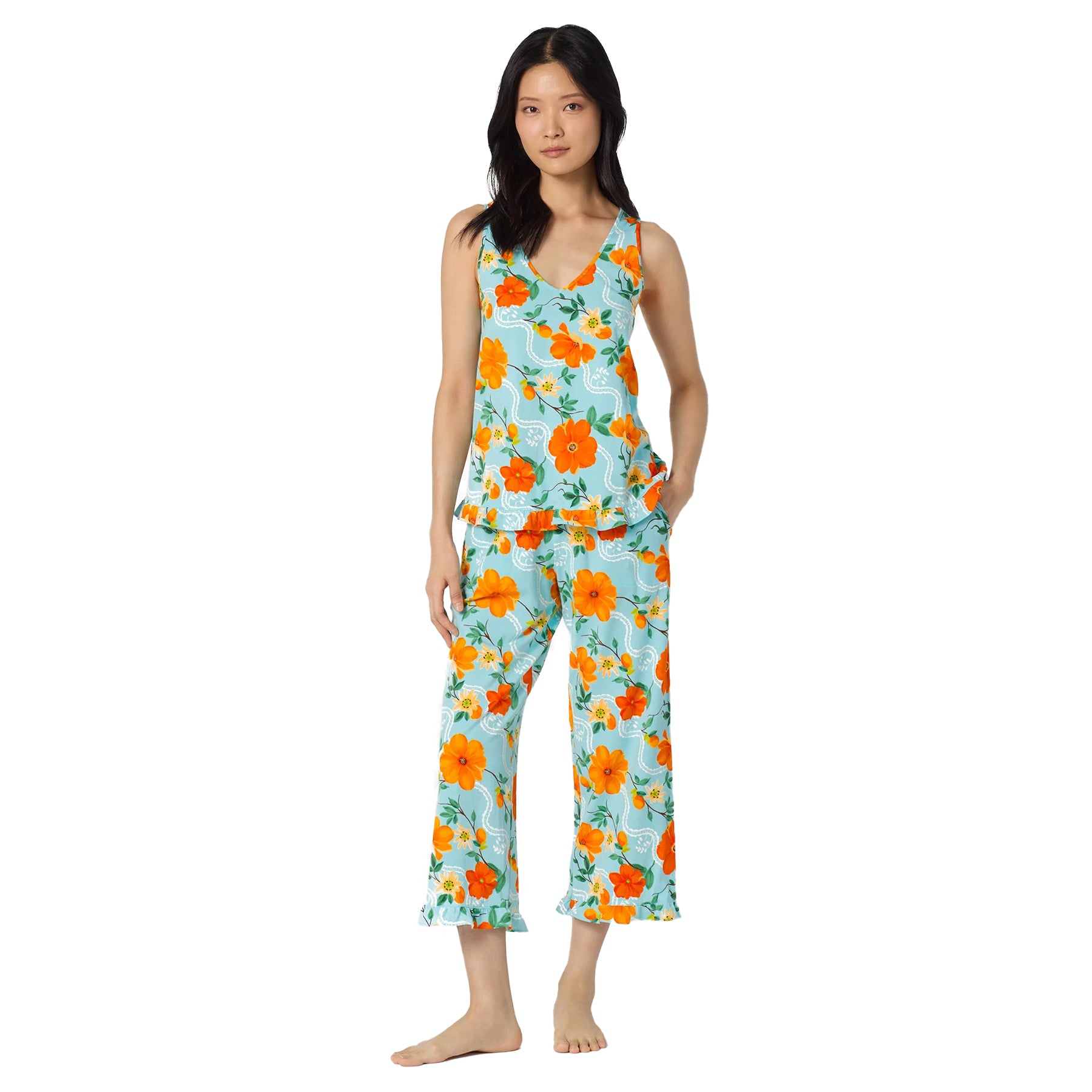 Woman wearing a sleeveless aqua blue pyjama set with vibrant orange floral print, featuring a V-neck tank top with ruffle hem and cropped wide-leg pants.