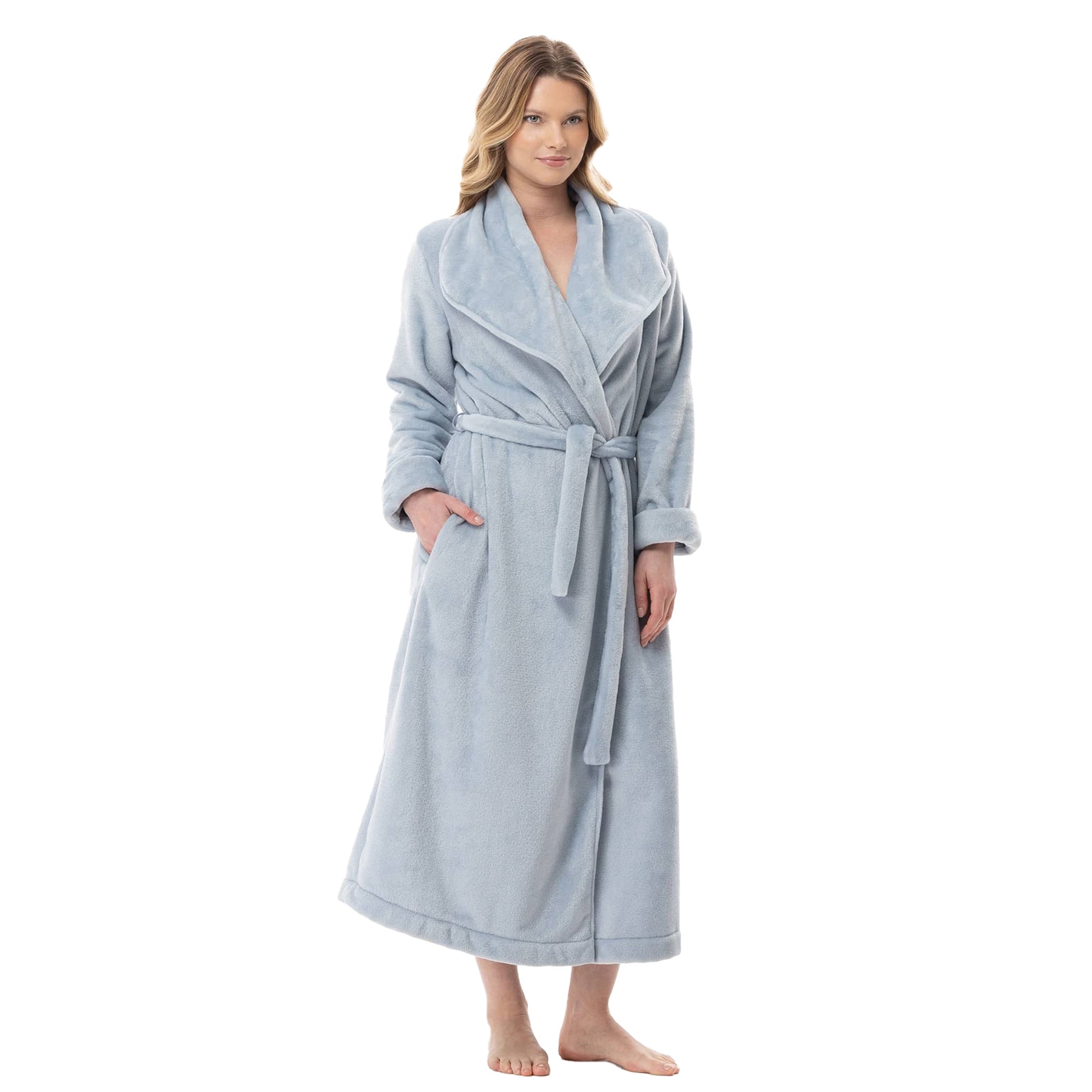 Woman wearing a long sky-blue fleece robe with shawl collar and tie belt, standing with hands in pockets.