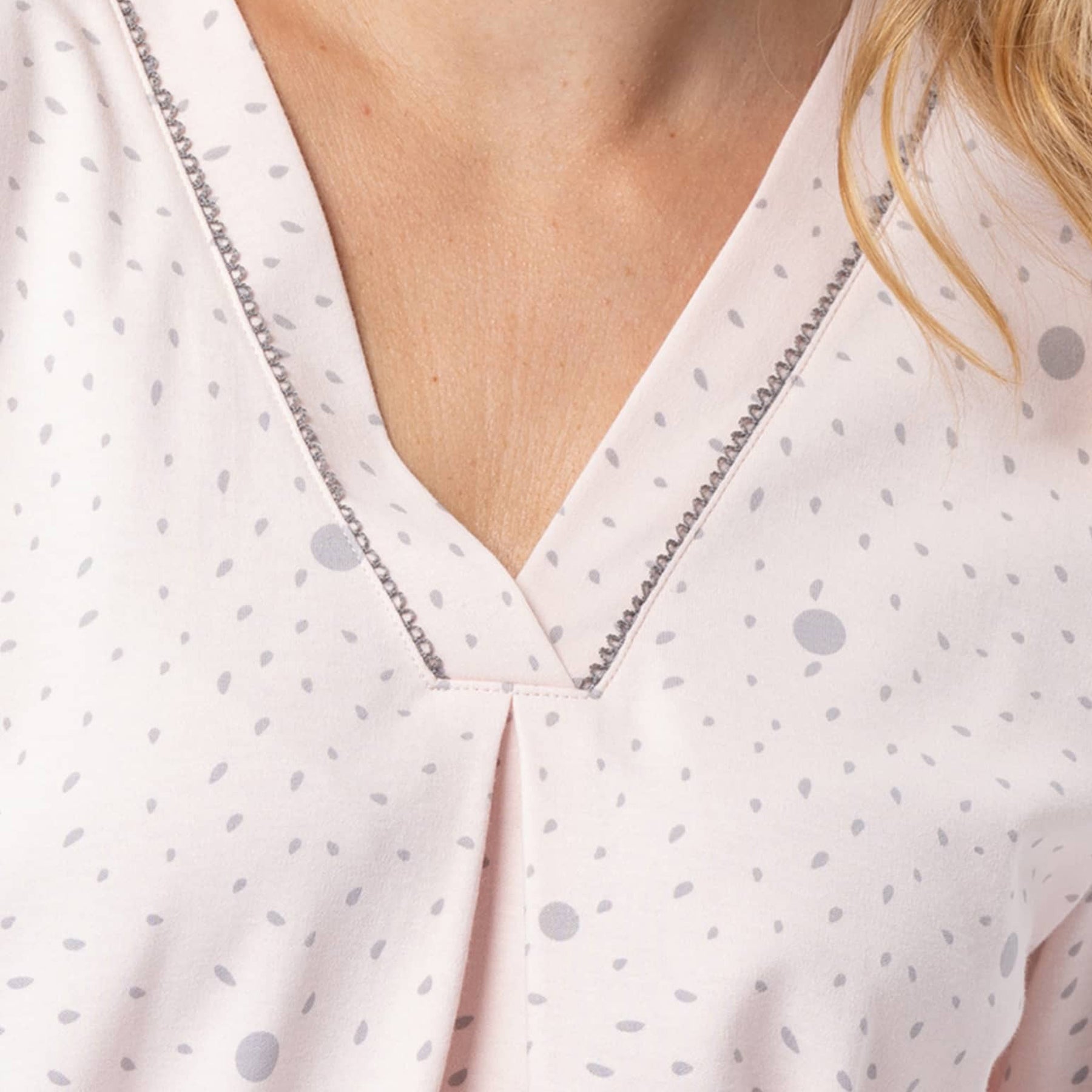 Close-up of a person wearing a light-colored blouse with a subtle pattern.