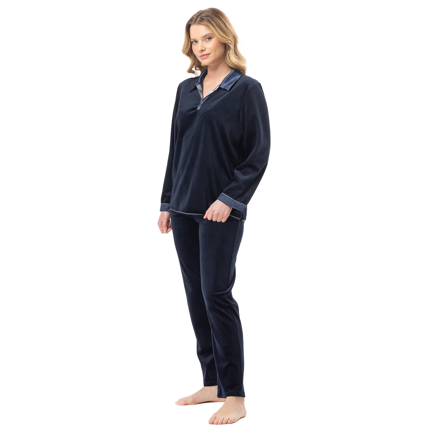 Woman wearing navy velour pyjama set with satin-trimmed collar and cuffs, standing barefoot.