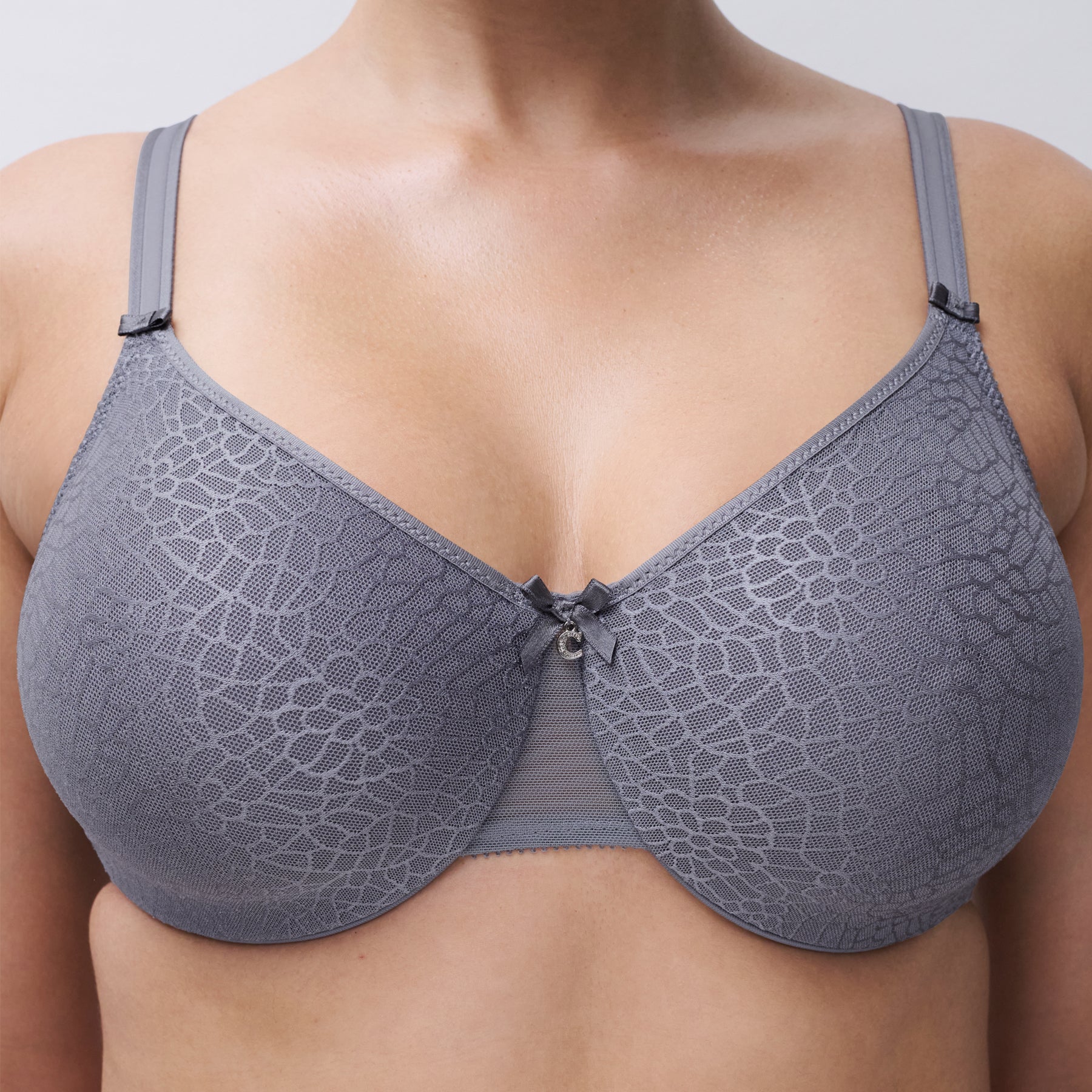 Close-up of Chantelle C Magnifique minimizer bra in New Smoke Grey featuring seamless floral textured cups and delicate centre bow detail.
