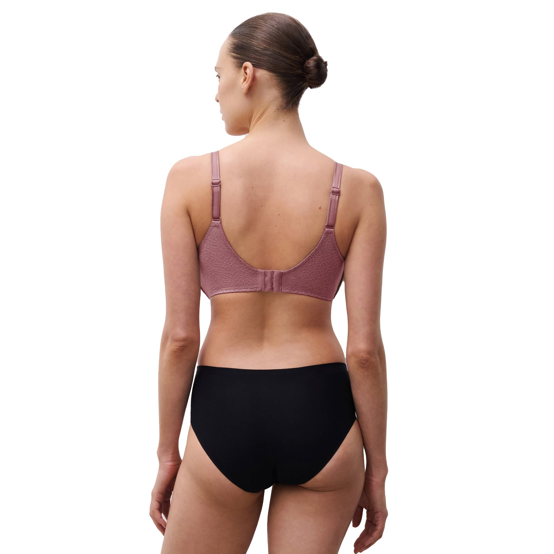 Woman wearing a purple bra and black underwear on a white background