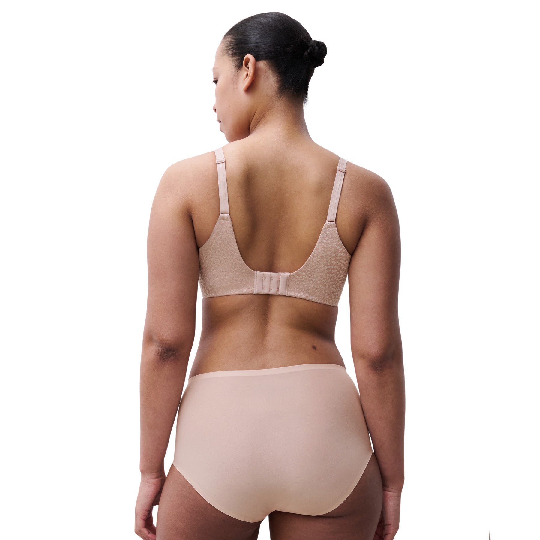 Back view of woman wearing soft pink minimizer bra and coordinating brief, highlighting smooth back fit.