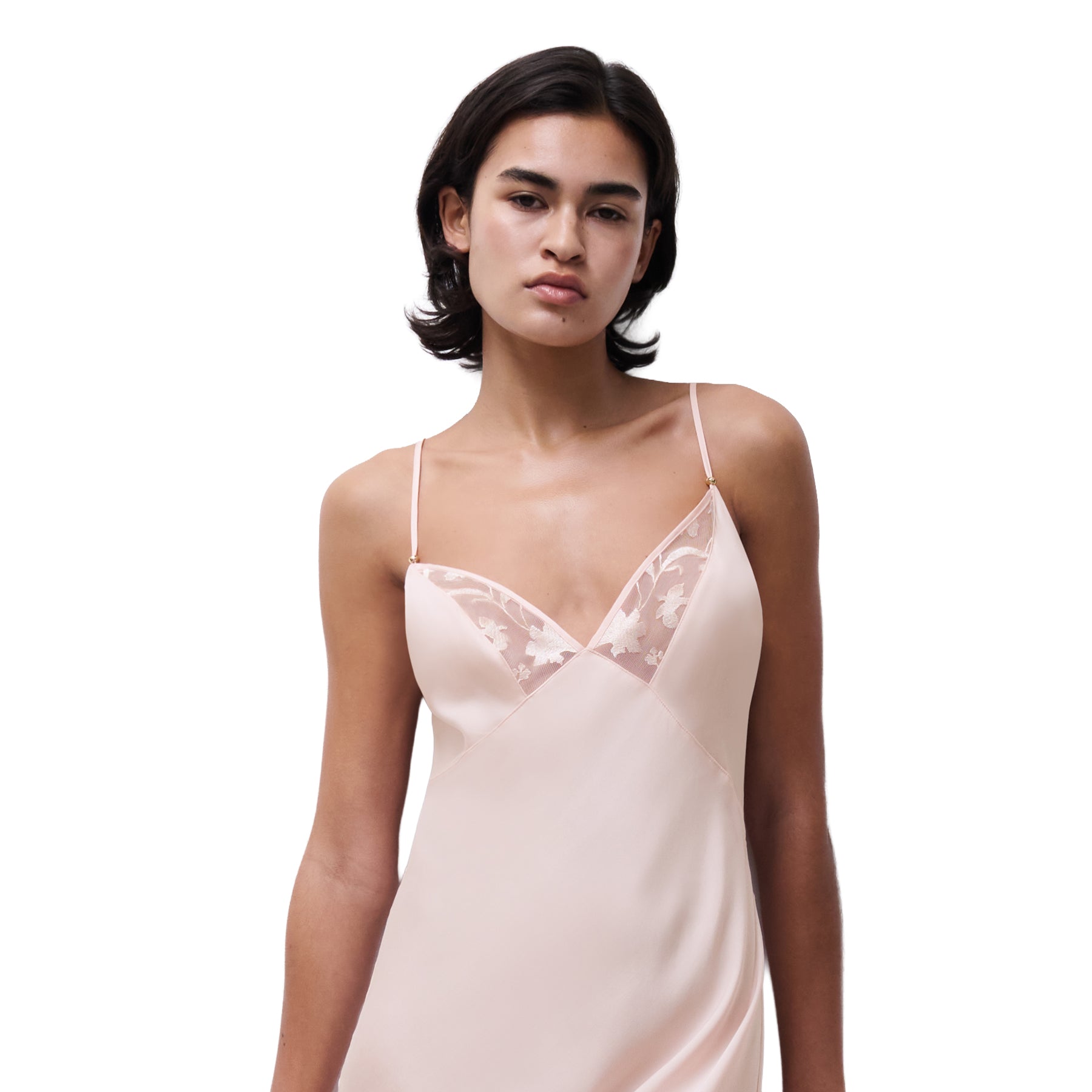 Close-up of blush pink slip dress featuring sheer lace V-neck panels and fine straps, shown on model.