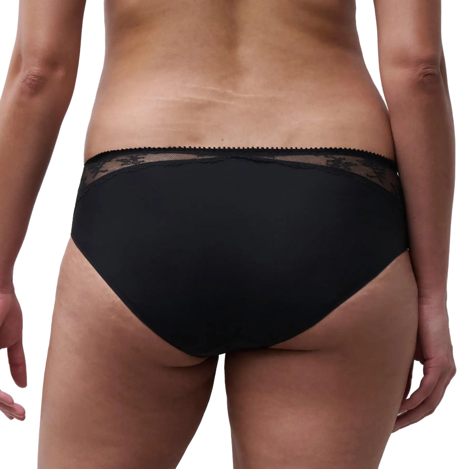Model wearing a black full brief with smooth full-coverage back and sheer floral lace trim along the waistband.