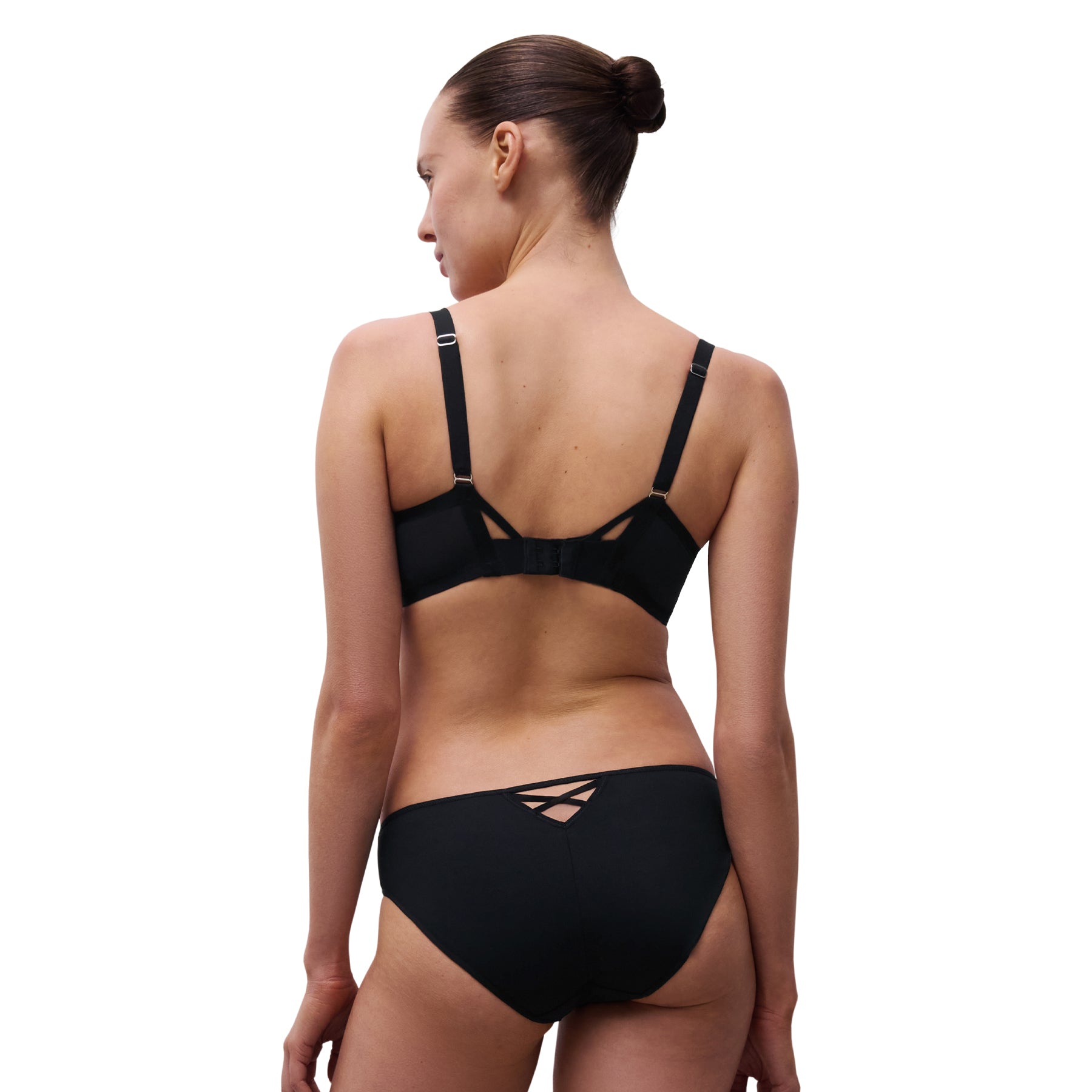 Back view of model wearing black floral embroidered plunge bra and solid black bikini brief with criss-cross strap detail.