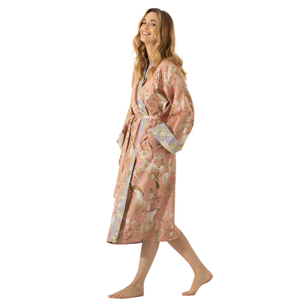 Woman modelling a dusty pink floral and bird print long robe with lavender contrast cuffs and trim, finished with a tie waist.