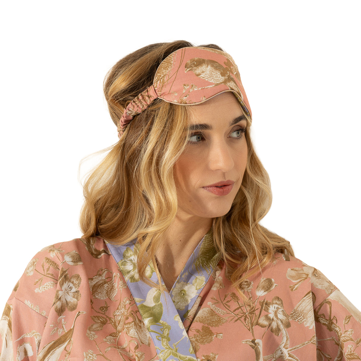 Close-up of dusty pink bird print sleep mask with gathered elastic band, styled with a coordinating floral robe.