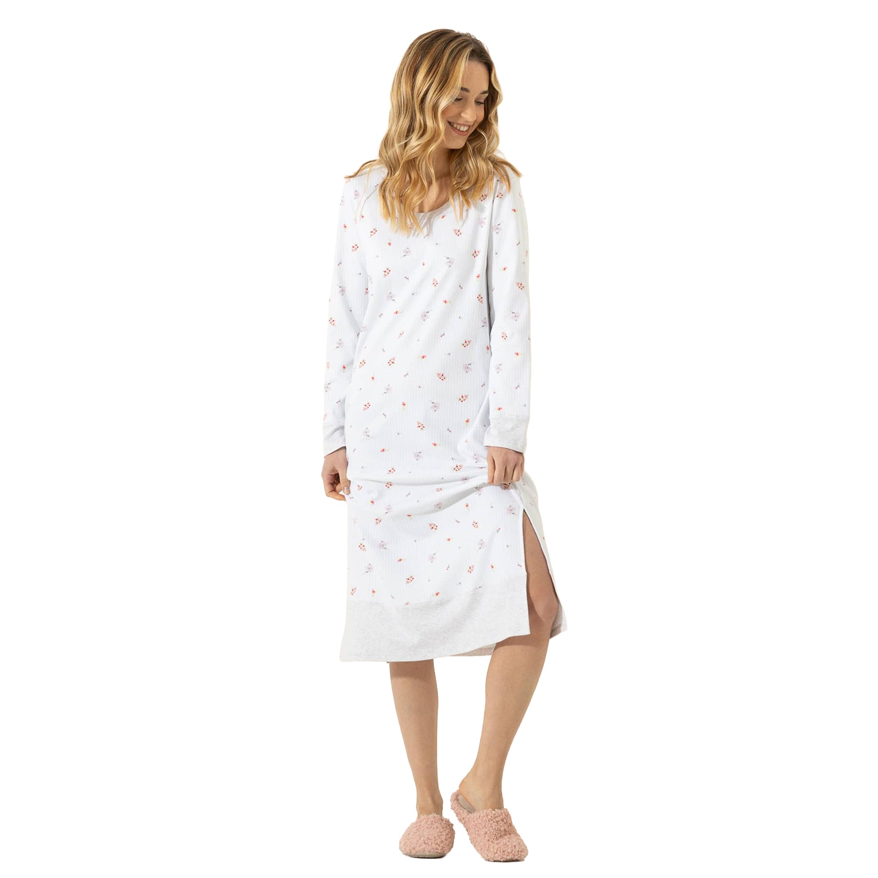 Woman wearing a white mini floral long-sleeve nightgown with a relaxed fit, side slit, and soft grey hem.