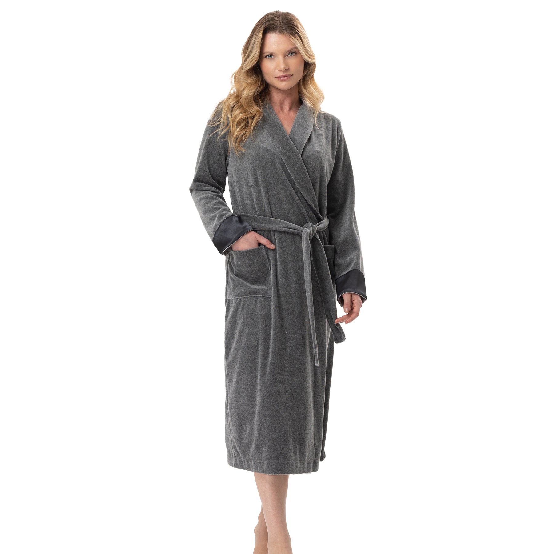 Woman wearing a long grey velour robe with satin trim and tie belt, standing with one hand in pocket.