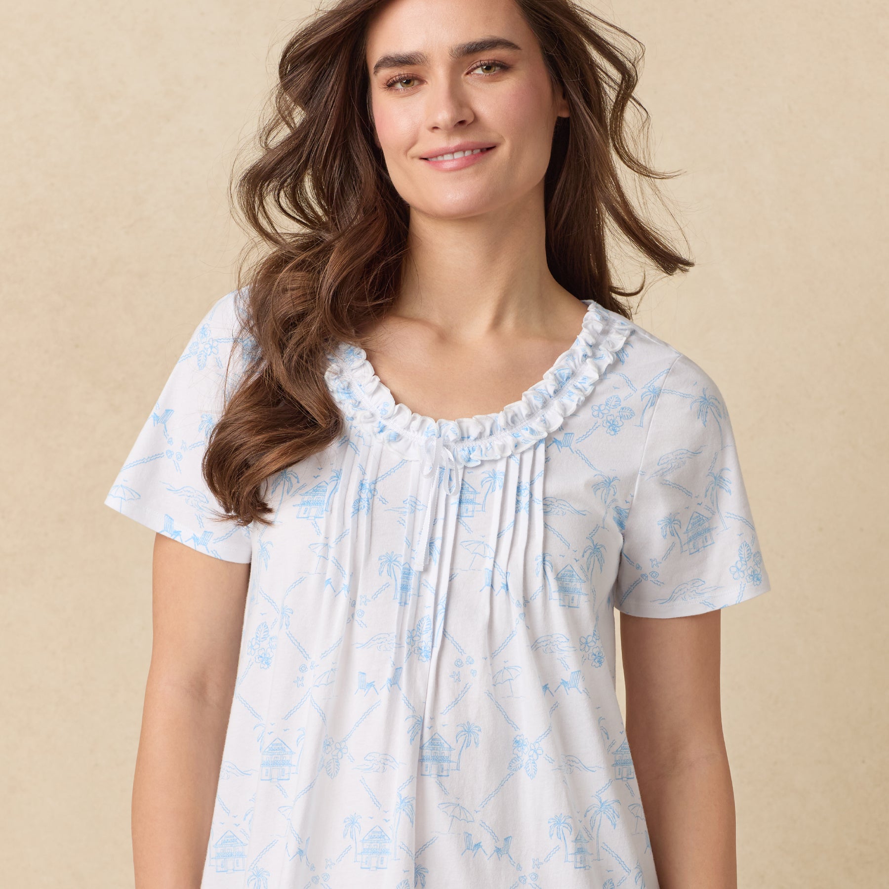 Woman smiling while wearing the nightgown, showcasing the ruffled neckline and delicate beach-themed pattern.