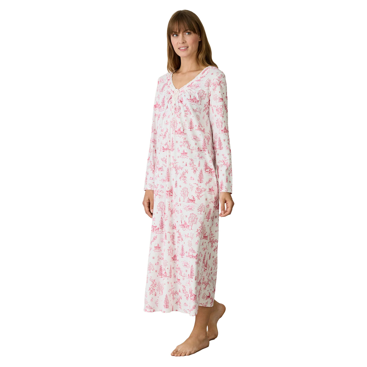 Woman wearing a Carole Hochman long white nightgown with a pink winter toile print, long sleeves, lace-trimmed V-neckline and relaxed silhouette.