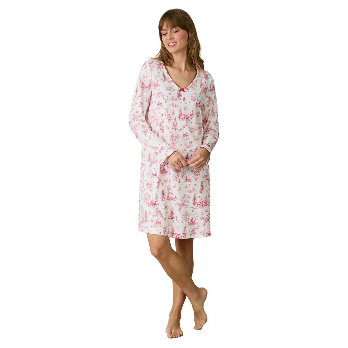 Carole Hochman long-sleeve chemise in white with a pink winter toile print featuring snowy cottages, trees and woodland scenes, a V-neckline with red scalloped trim and a small red bow.