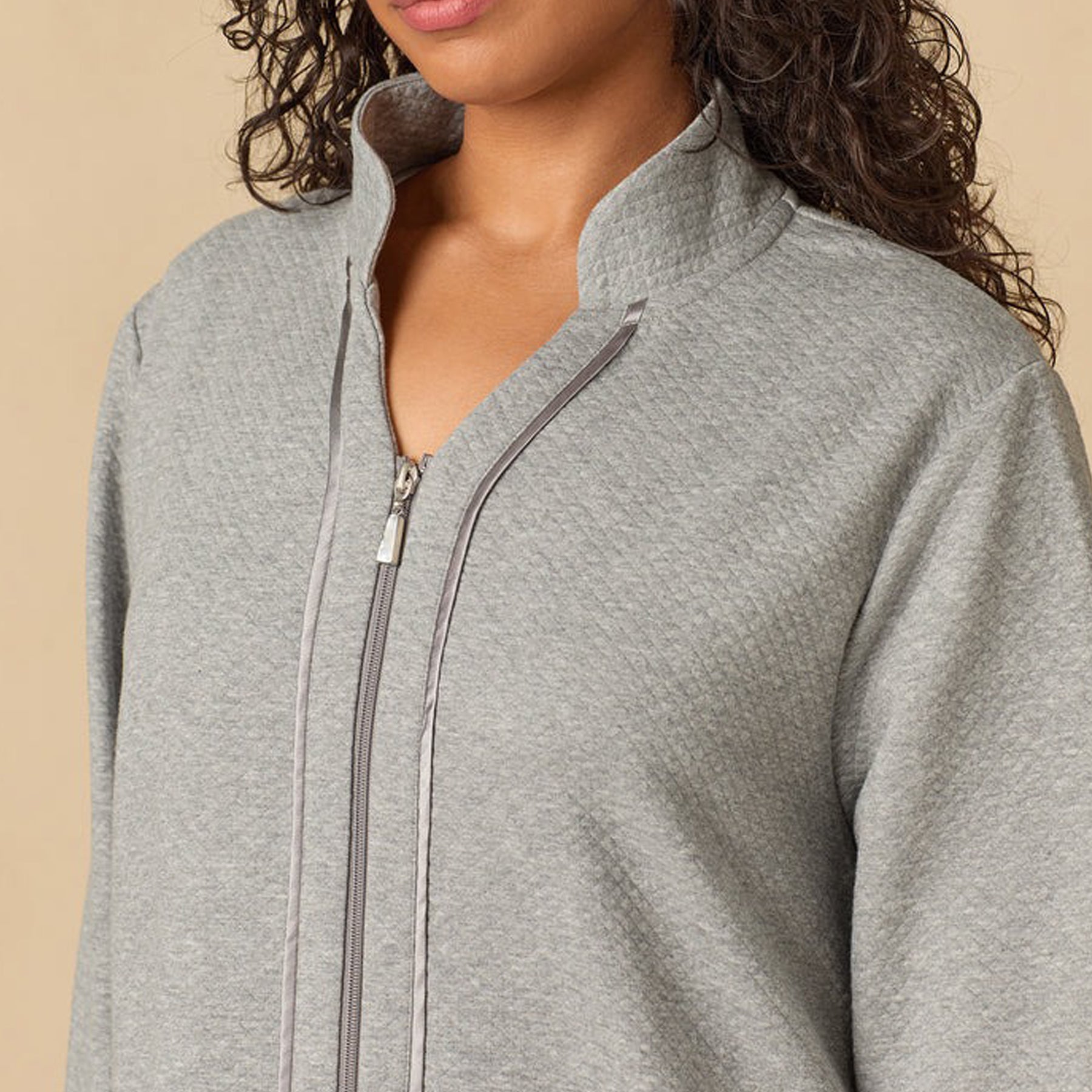 Gray zip-up hoodie worn by a person on a beige background