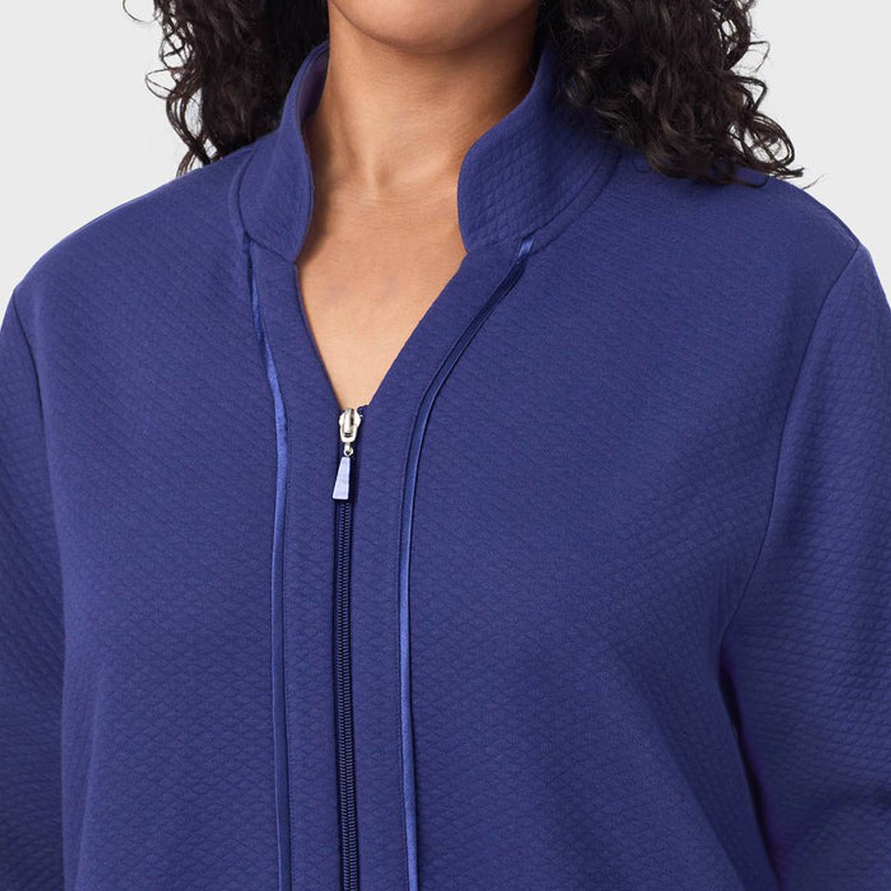 Close-up of a person wearing a blue zip-up jacket on a light gray background