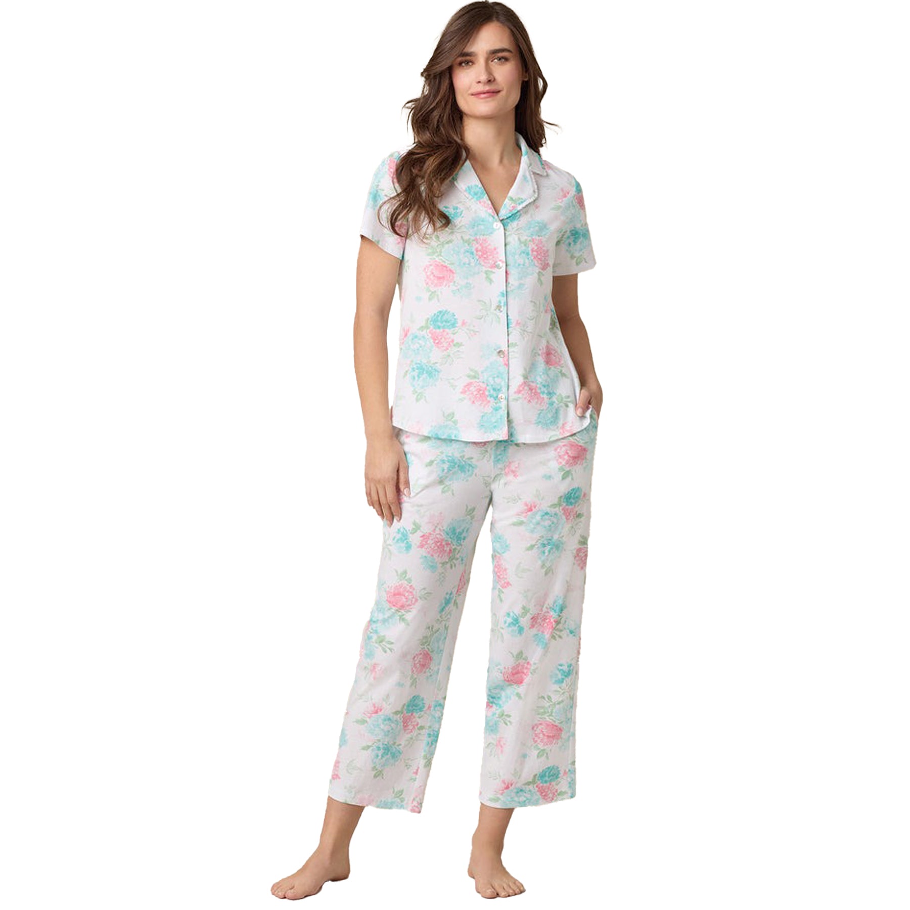 Woman wearing pastel floral short-sleeve cotton pyjama set with button-up top and ankle-length pants - front view.