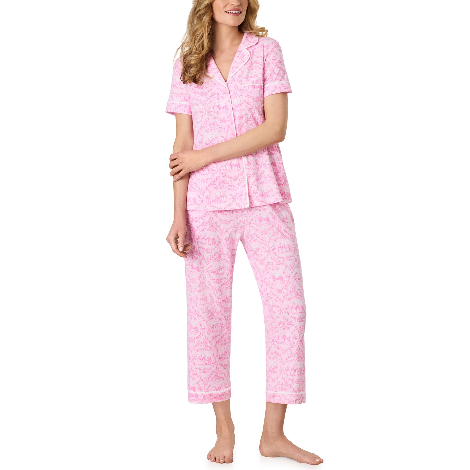 Model wearing the Carole Hochman pink pajama set featuring a button-front short sleeve top and cropped pants with an elegant floral elephant print.
