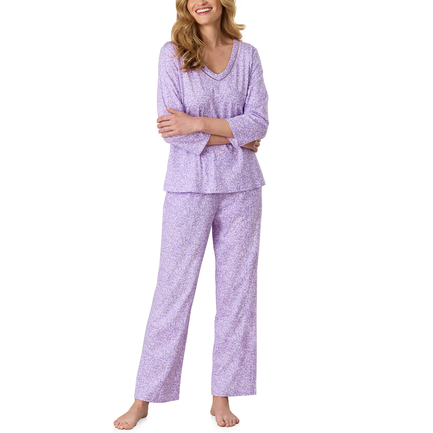 Model wearing the Carole Hochman two-piece pajama set with a relaxed long sleeve V-neck top and matching full-length pants in a lavender floral print.
