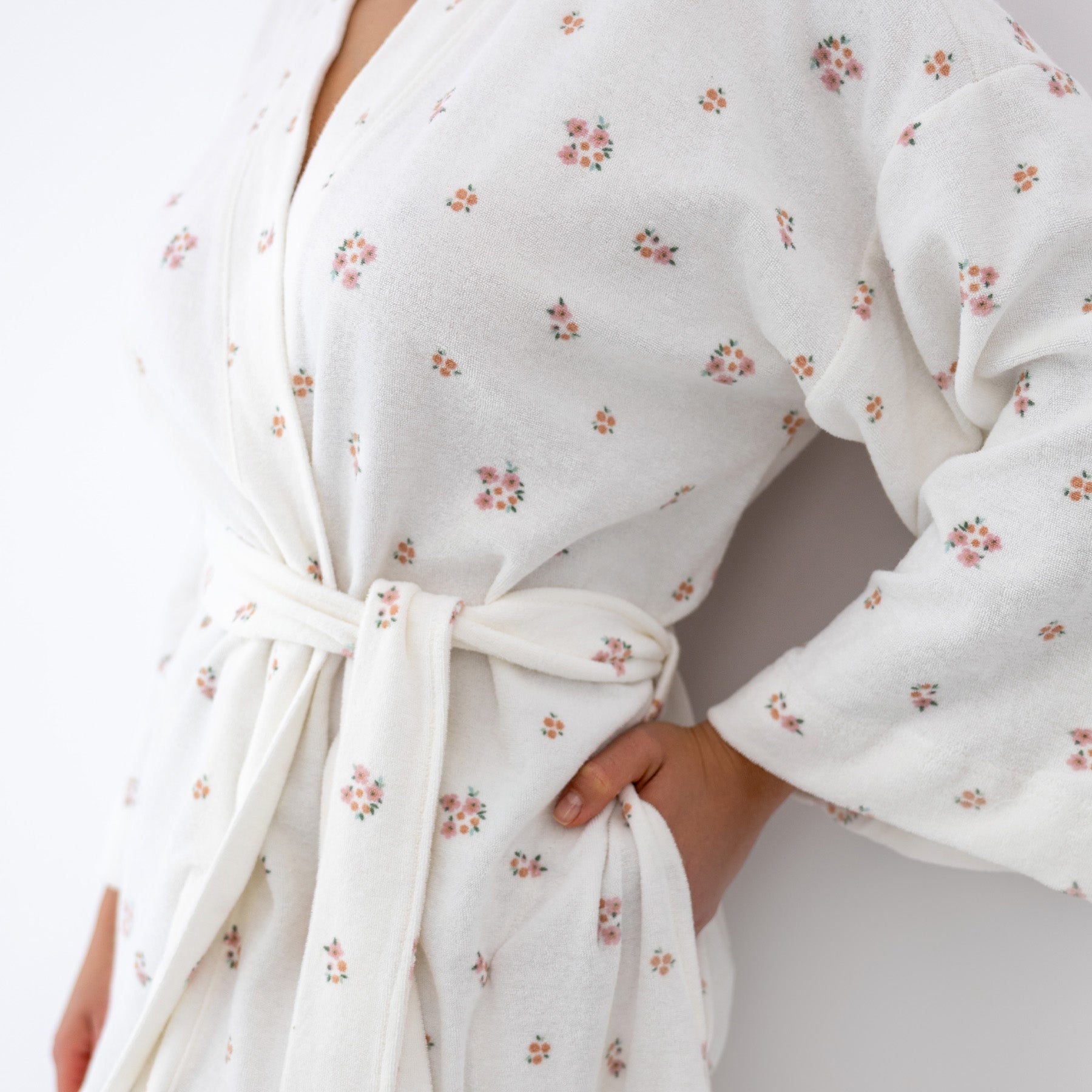 Close-up of white robe with delicate pink floral print, soft textured fabric, tie belt and side pocket detail