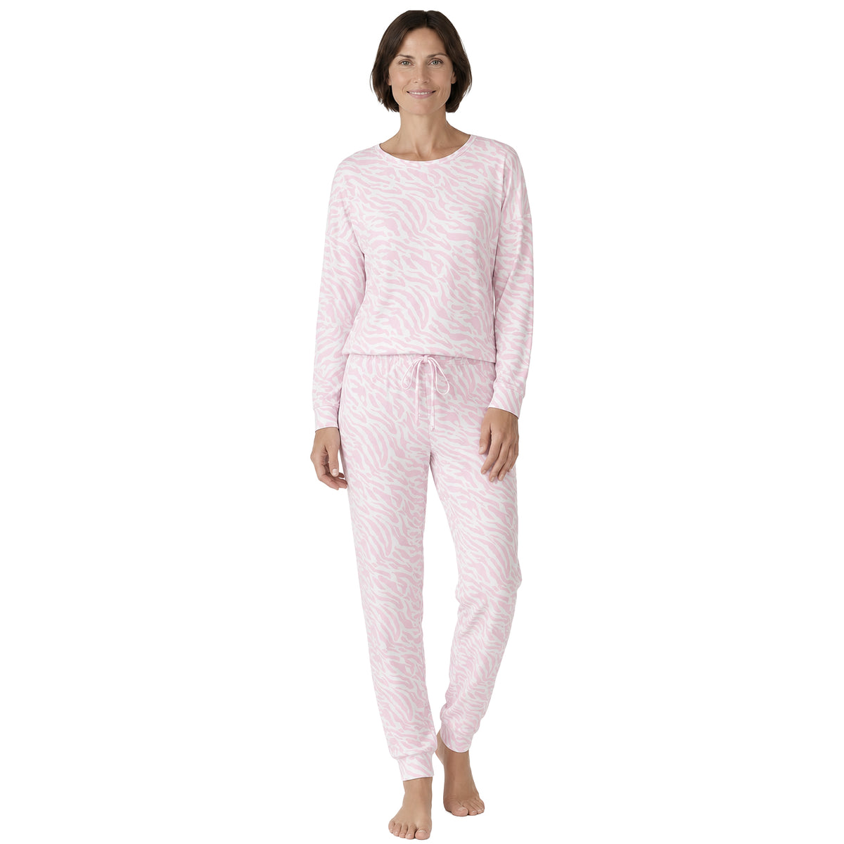 Model wearing a light pink and white zebra print pajama set with a long-sleeve crew neck top and matching drawstring jogger pants, front view.