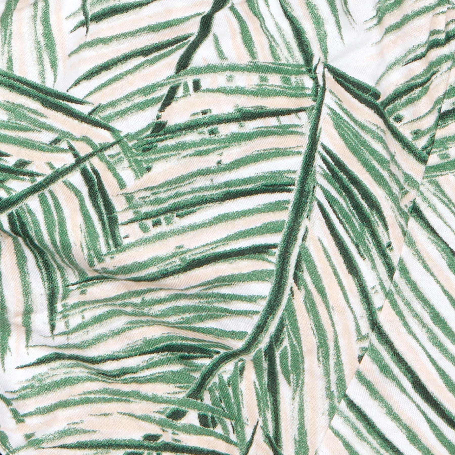 Close-up of green palm leaf print fabric showing soft texture and detailed tropical pattern.