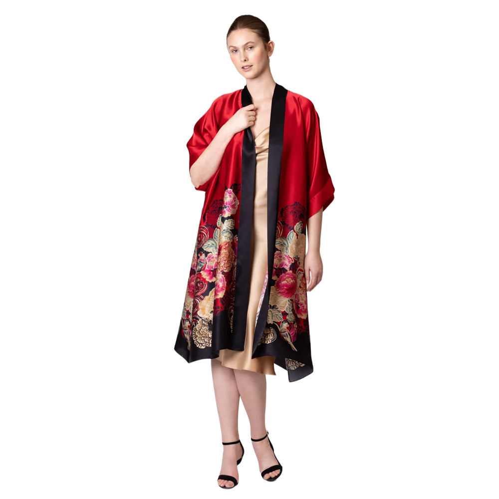 Model wearing Christine Crimson Moon Kimono in red satin with black trim, wide sleeves, and an elegant floral and bird print along the lower half.