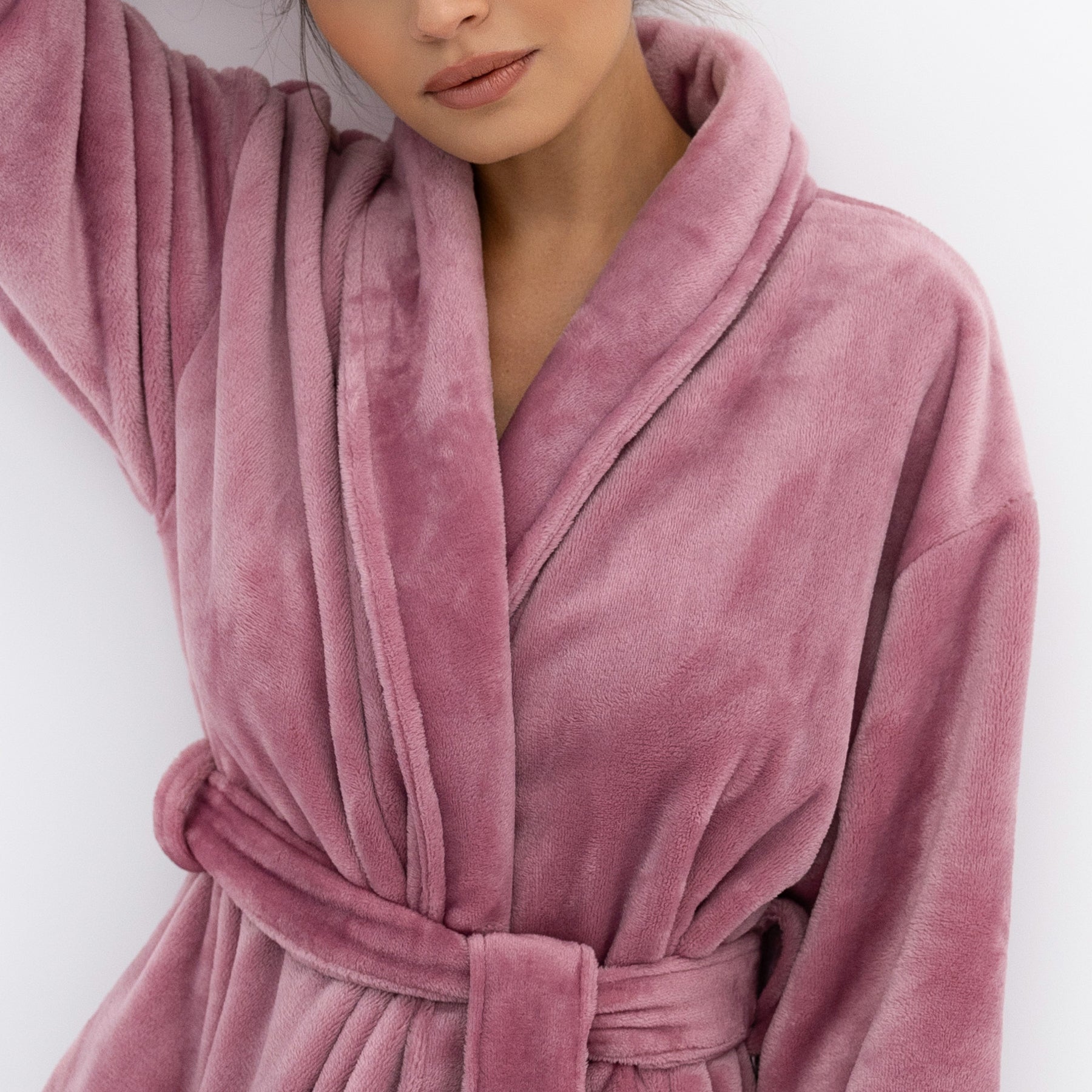 Close-up of rose-pink plush robe showing shawl collar, belt detail, and smooth velvety fabric.