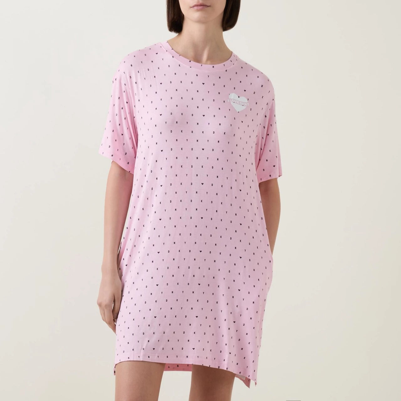 Short sleeve round neck sleepshirt in DKNY black mini logo and heart print on baby pink background. Front view on model.