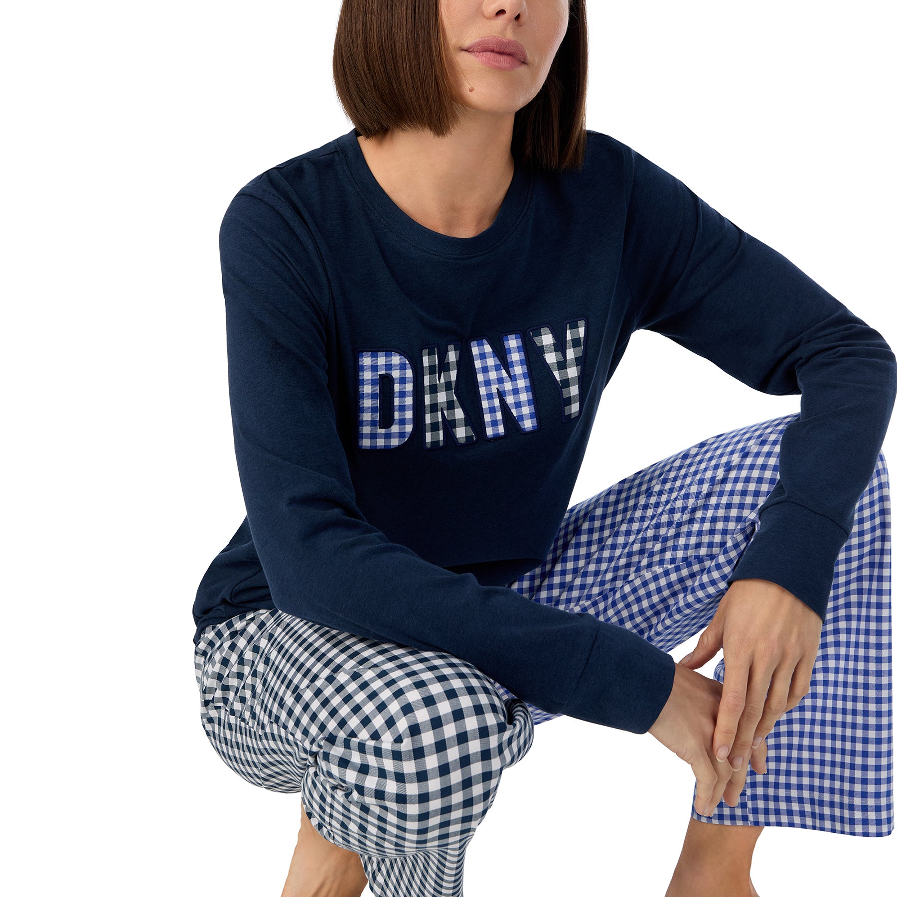 Long sleeve navy blue lounge top with DKNY gingham logo with matching black and blue gingham printed pants. Front view close up on model.