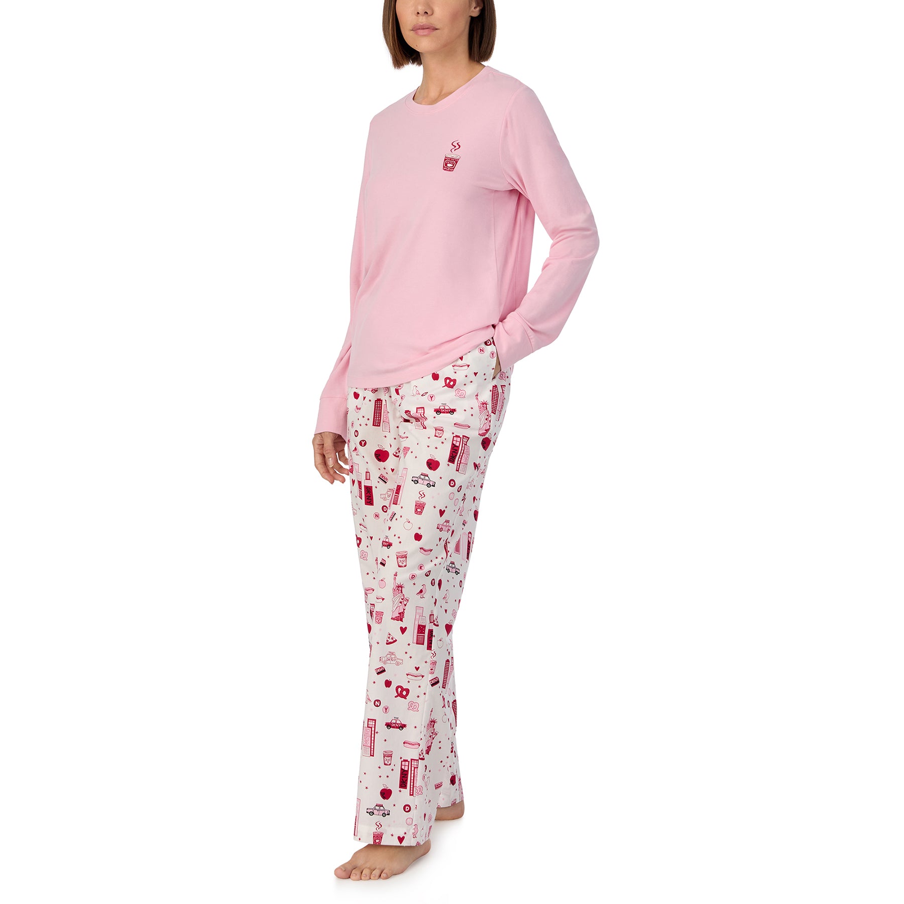 Long sleeve solid pink lounge top with matching pants printed with new york city items in red and pink on a white background. Front/side view on model.