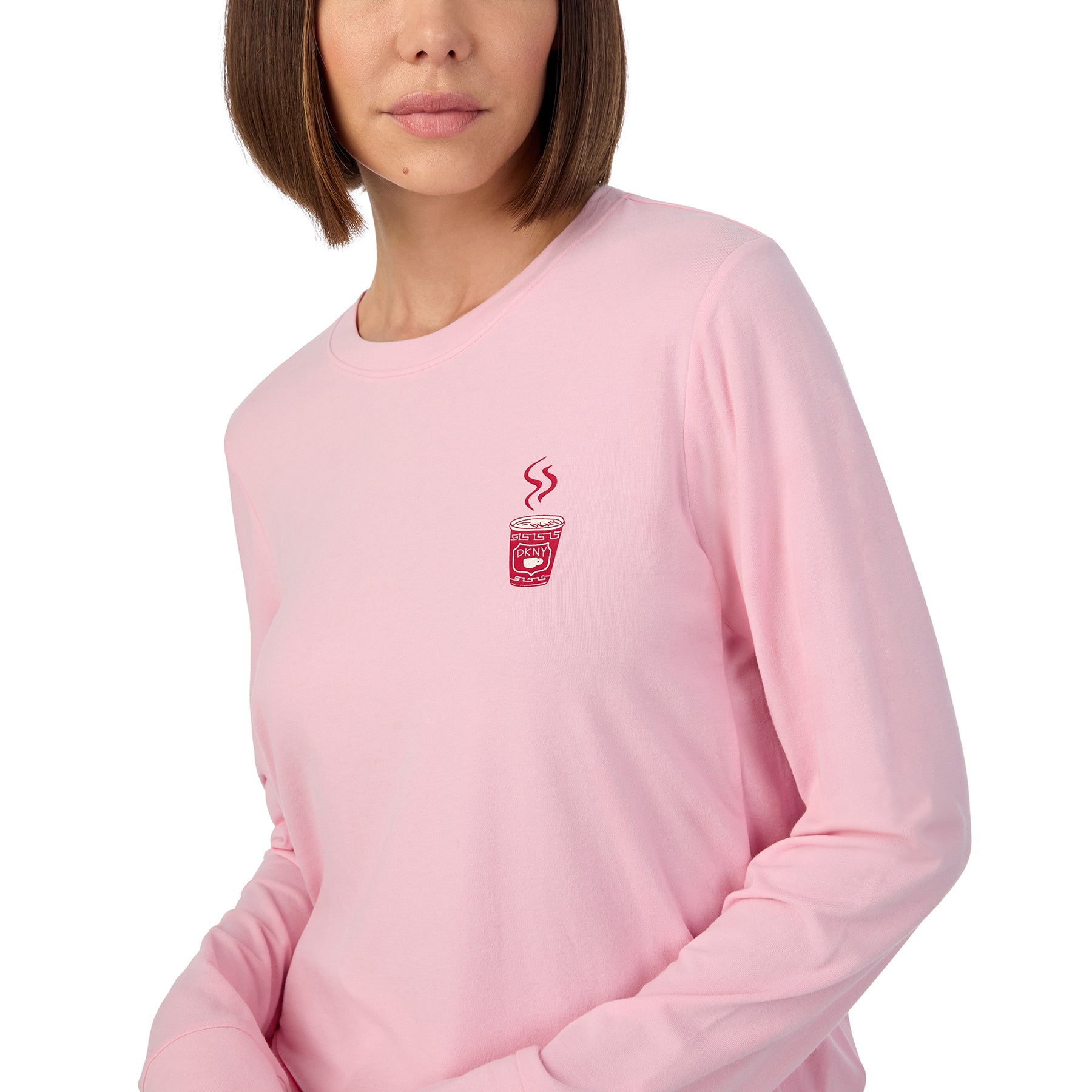 Long sleeve solid pink lounge top with matching pants printed with new york city items in red and pink on a white background. Front view of top close up on model.