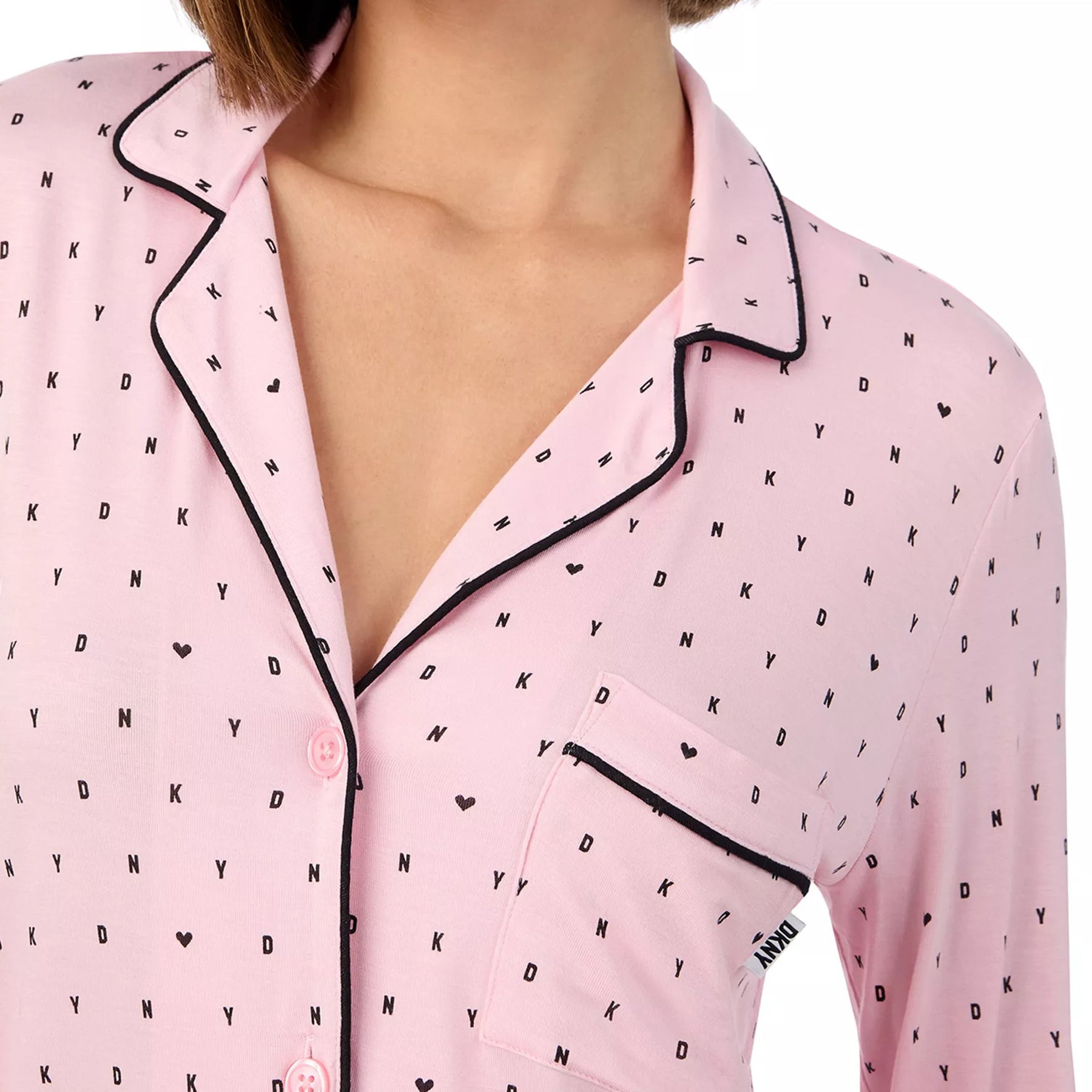 Classic button up 2-piece pyjama set in DKNY black mini logo and heart print on baby pink background. Front view close up on model.