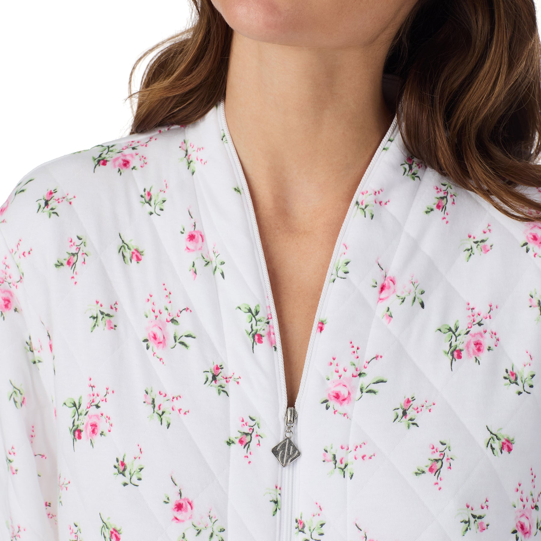Close-up of a white quilted robe with a pink floral print, featuring a zip-front neckline and softly padded fabric.