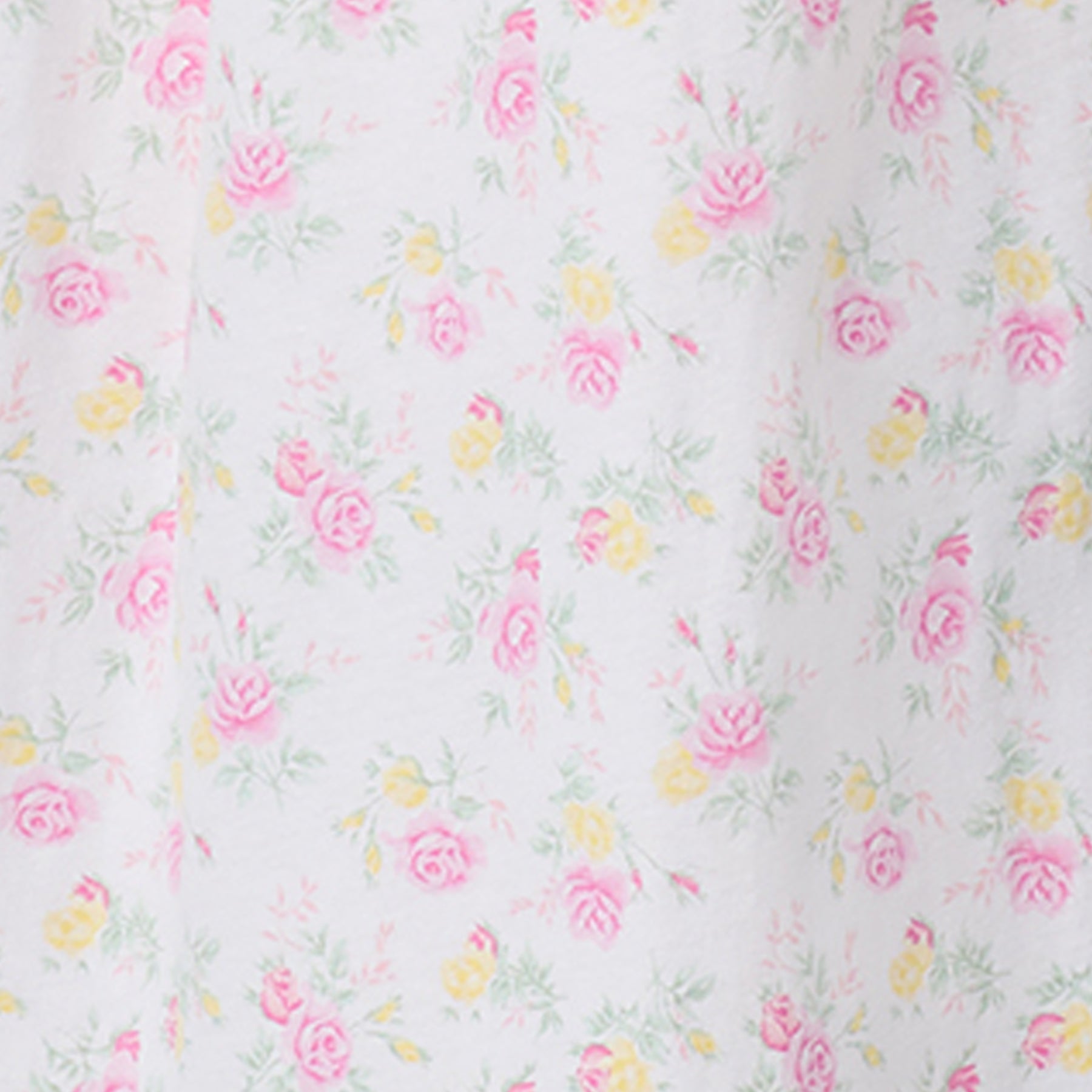 Close-up of pastel floral print fabric featuring pink and yellow roses on white background.