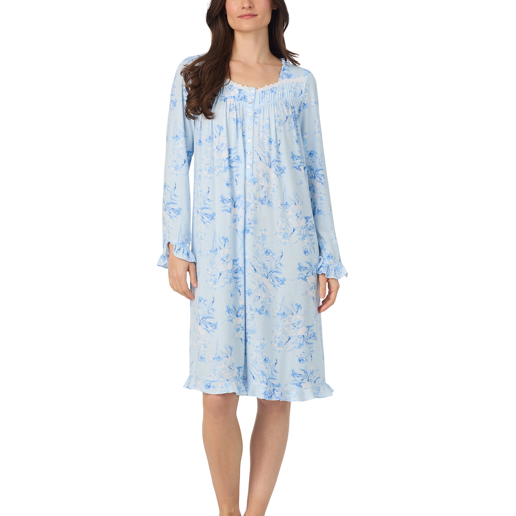 Front view of a woman wearing a light blue floral long-sleeve nightgown with ruffled cuffs and hem.