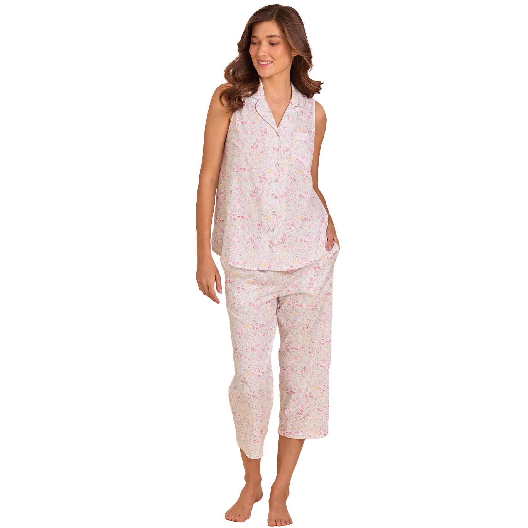 Woman wearing a sleeveless floral cotton pyjama set with cropped pants and button-front top in soft pink print.