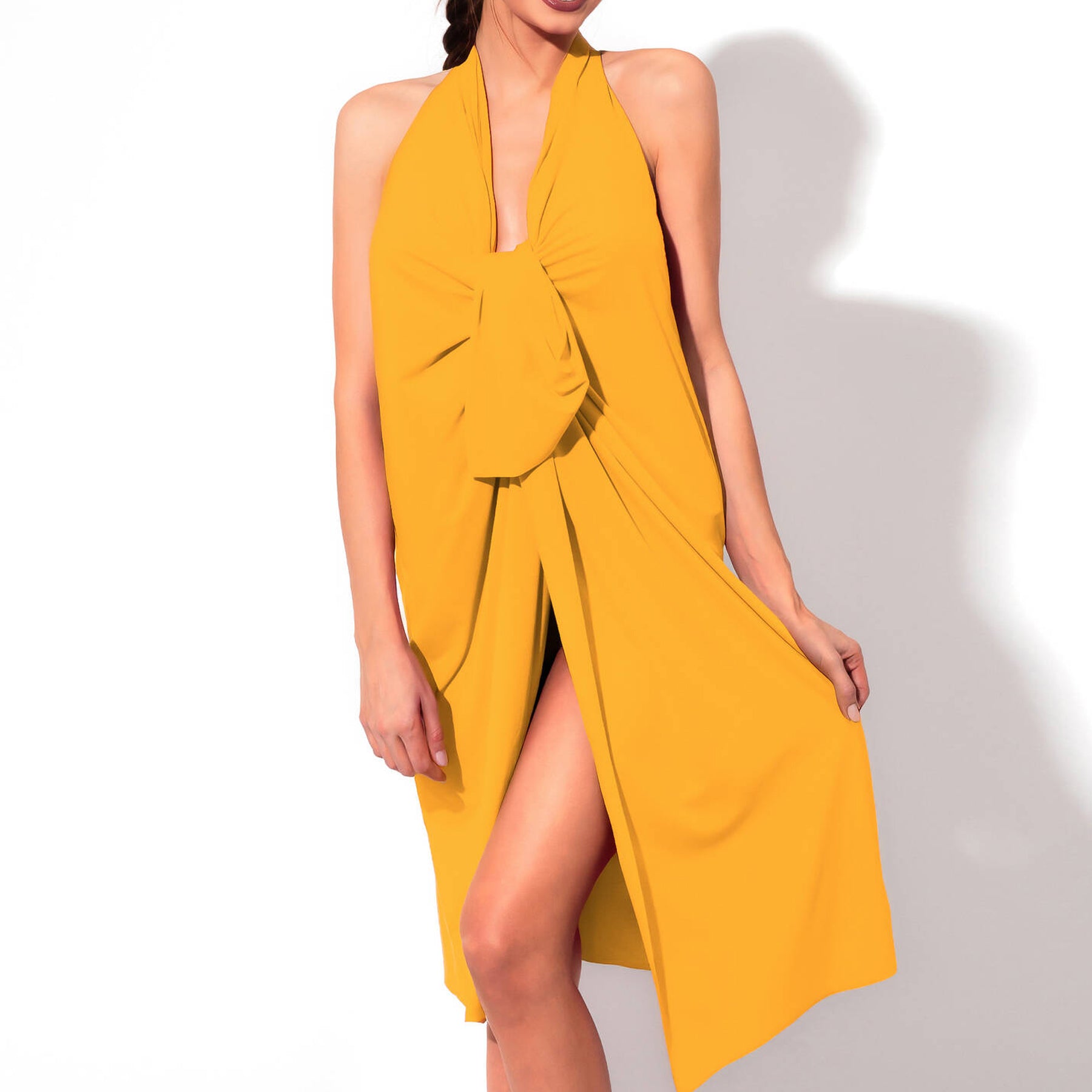 Model wearing a yellow halterneck beach cover-up with a draped front and front slit, styled over swimwear.