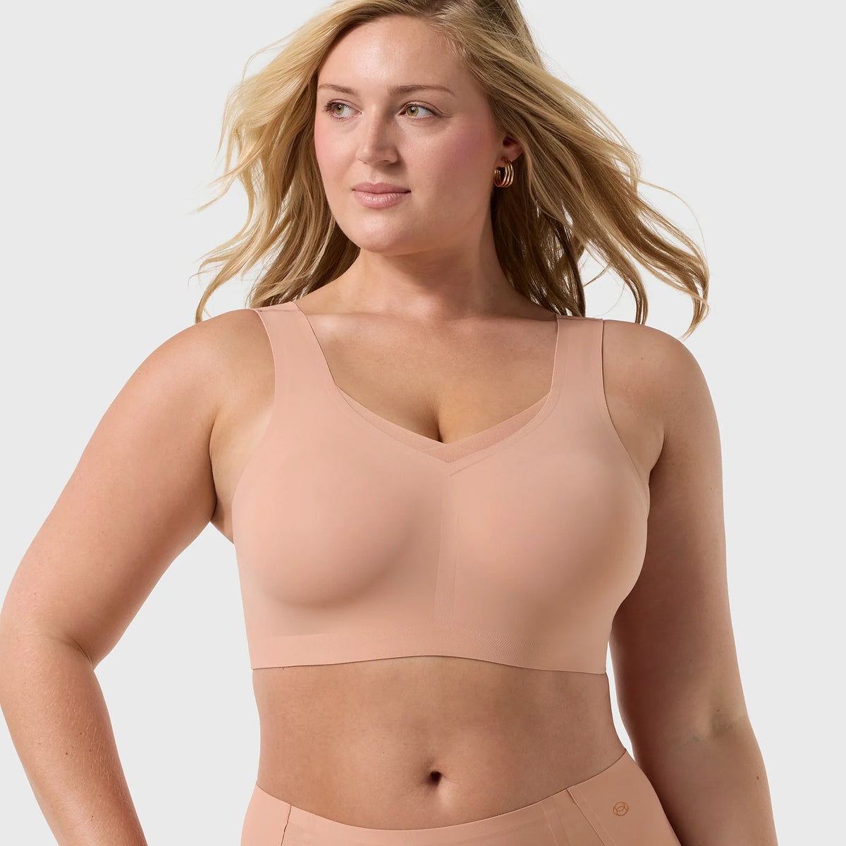 Blonde model wearing the Evelyn & Bobbie Defy Wireless Bra Style 1865 in Himalayan Salt, showcasing smooth wireless cups, wide straps, and a seamless supportive fit.