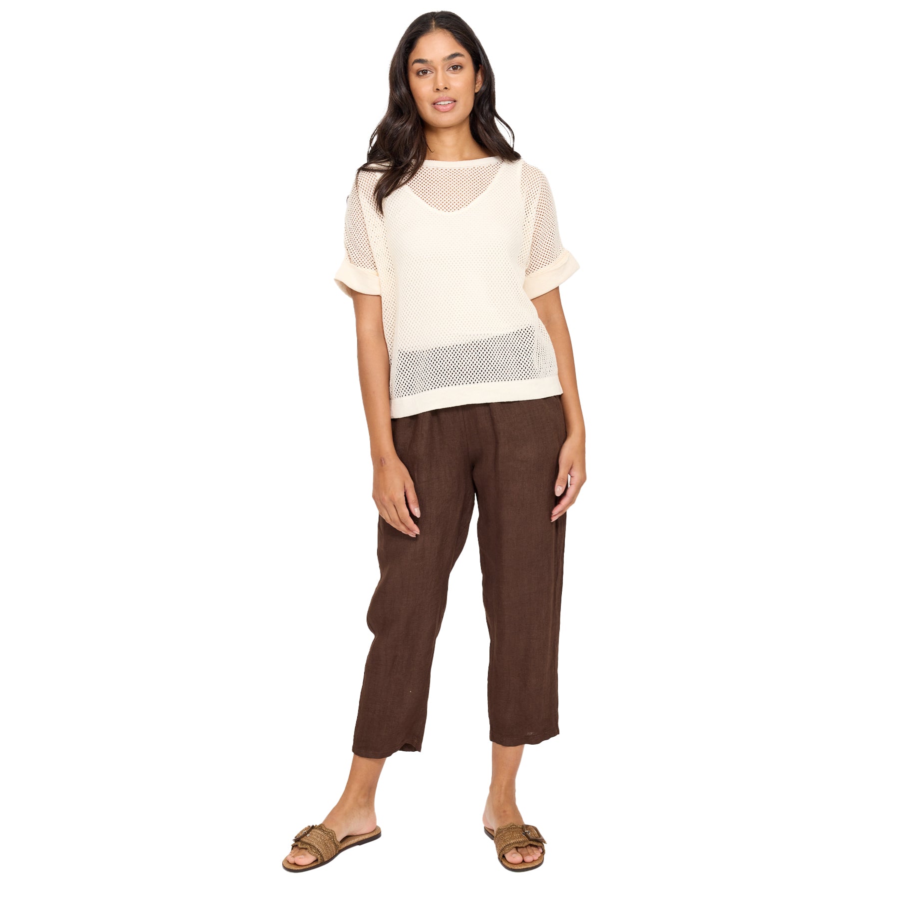 Woman wearing a beige top and brown pants on a white background