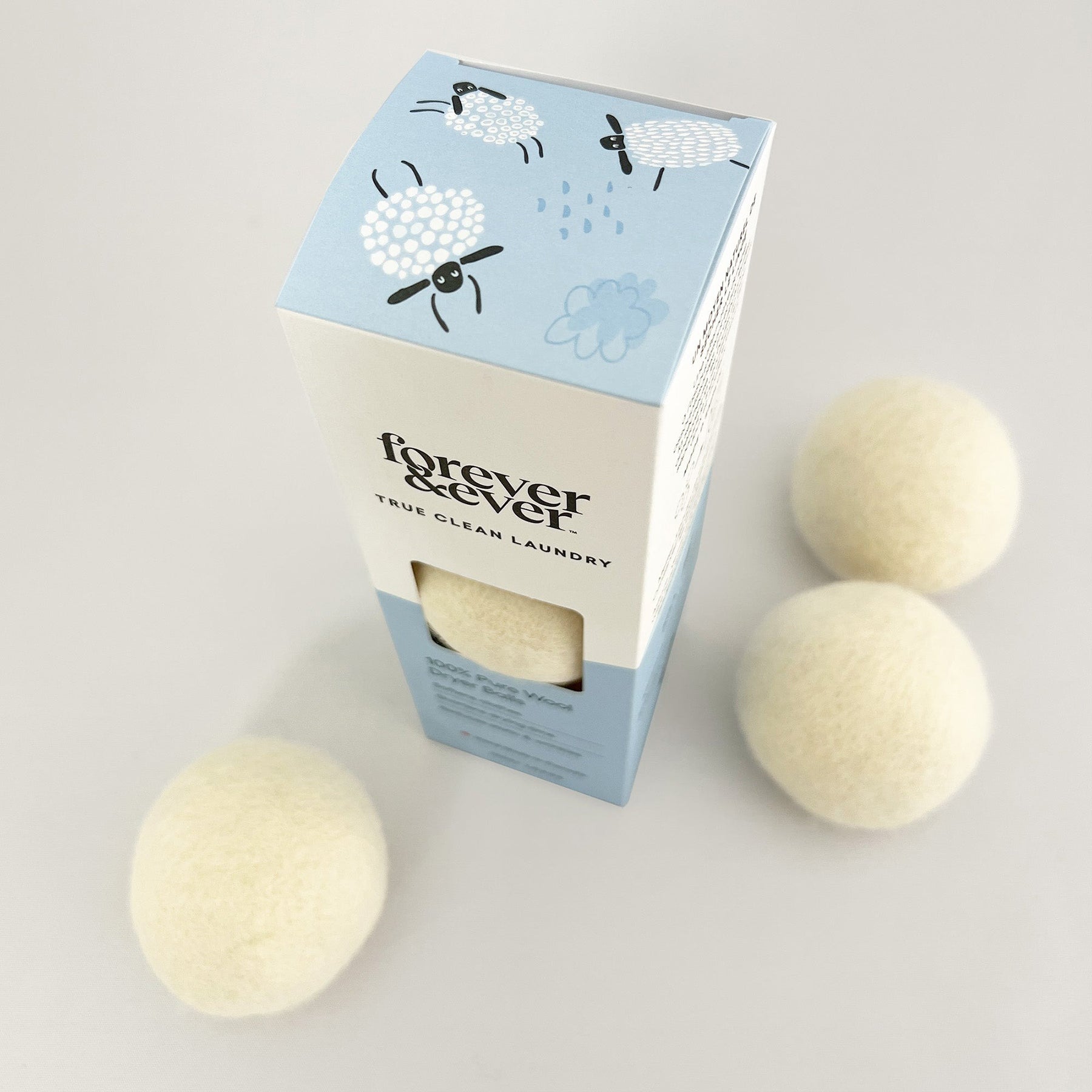 Close-up of Forever & Ever 100% pure wool dryer balls with eco-friendly packaging featuring illustrated sheep design.